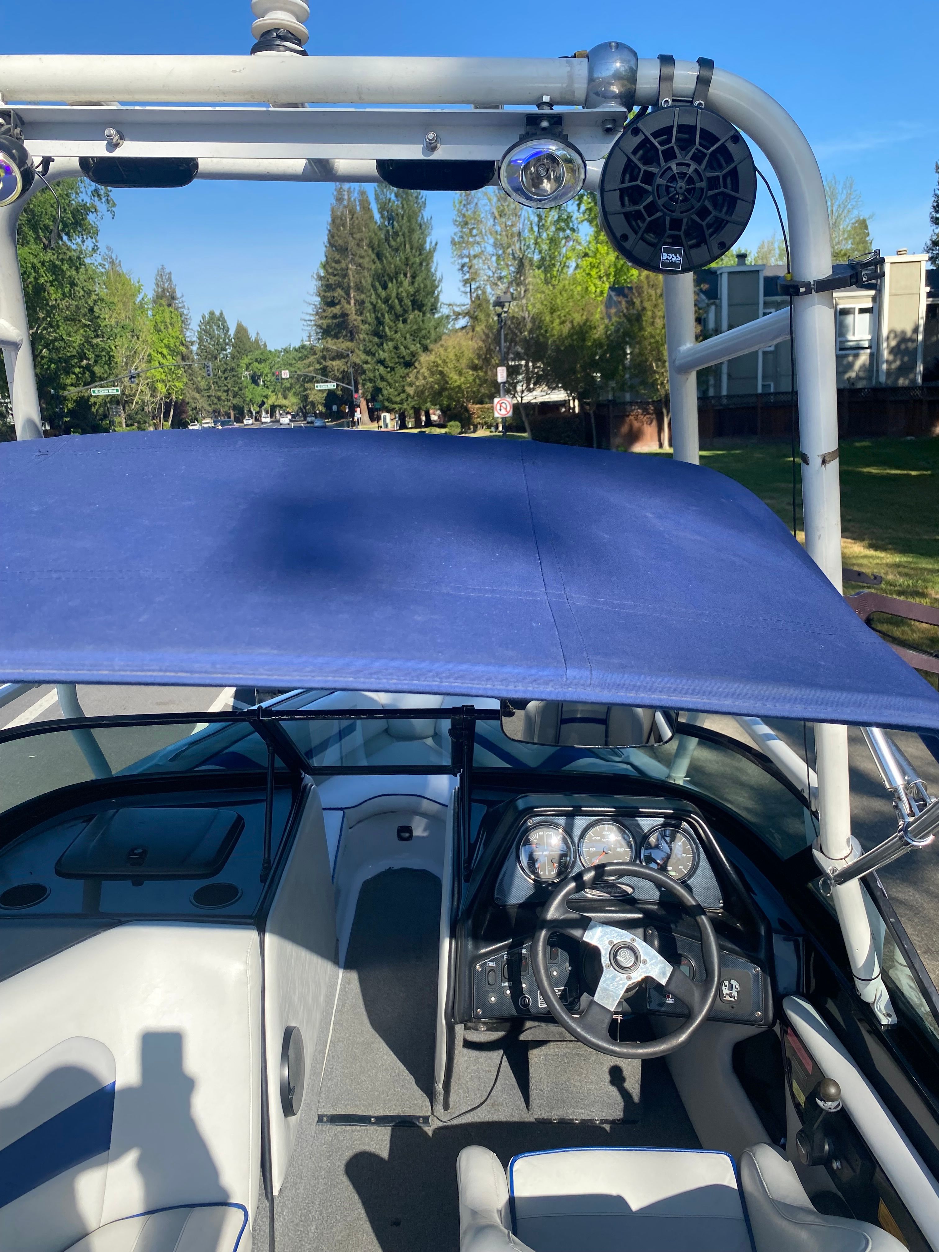 Interior view of a 2001 Sanger V210 boat with blue canopy and steering console.