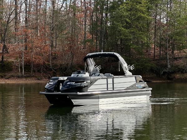 2025 Montara Surf Boss 2.0 25 boat on a calm lake, surrounded by trees.