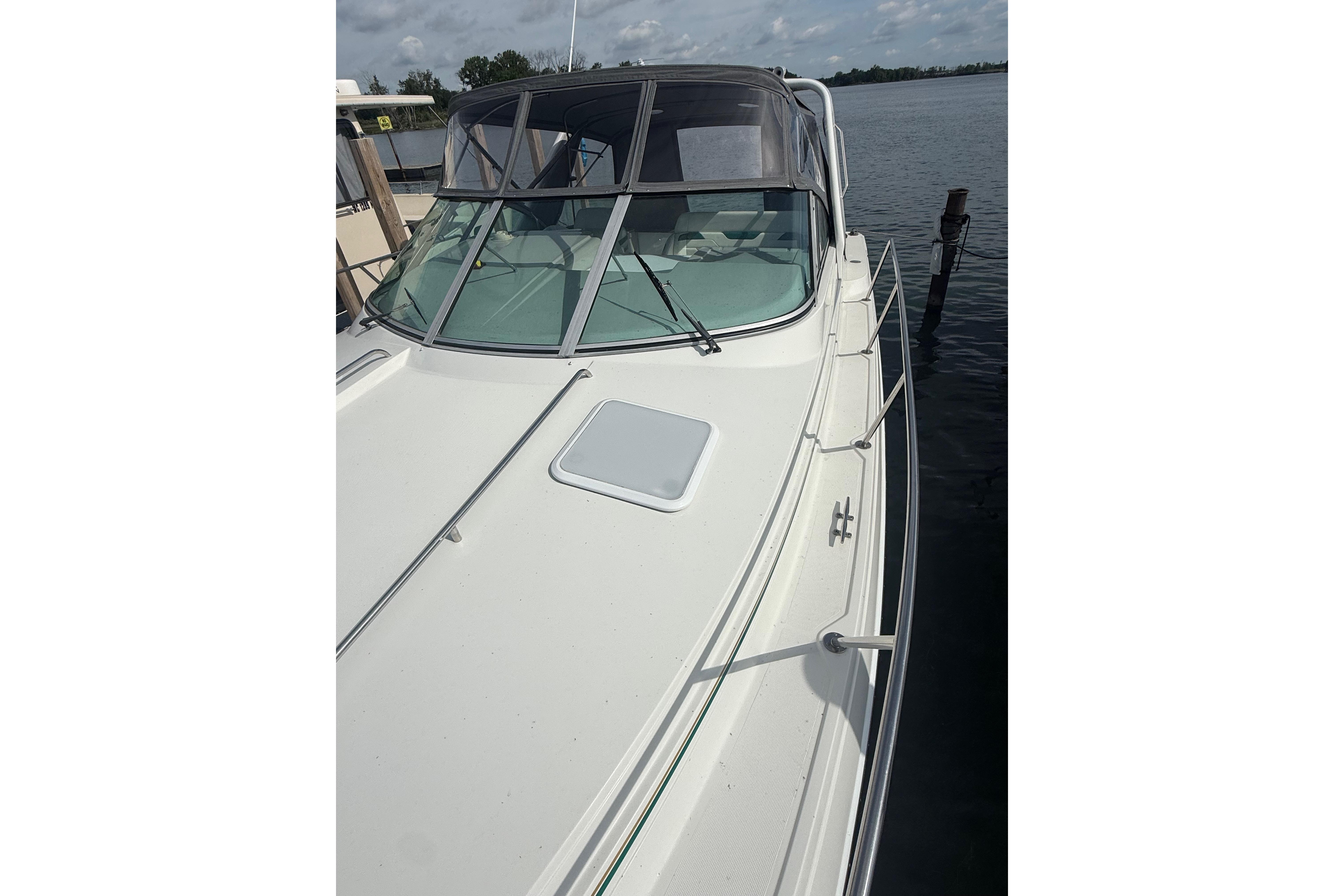 1999 Formula 34 Performance Cruiser docked on a calm lake under a cloudy sky.