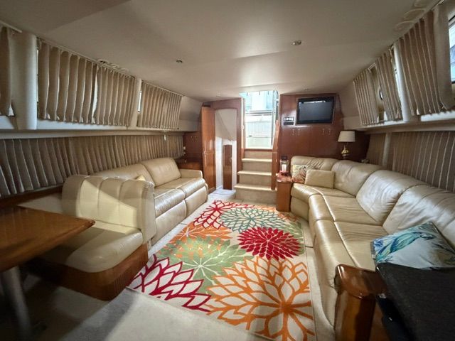 Interior of the 2005 Carver 44 Cockpit Motor Yacht with beige leather sofas and colorful rug.