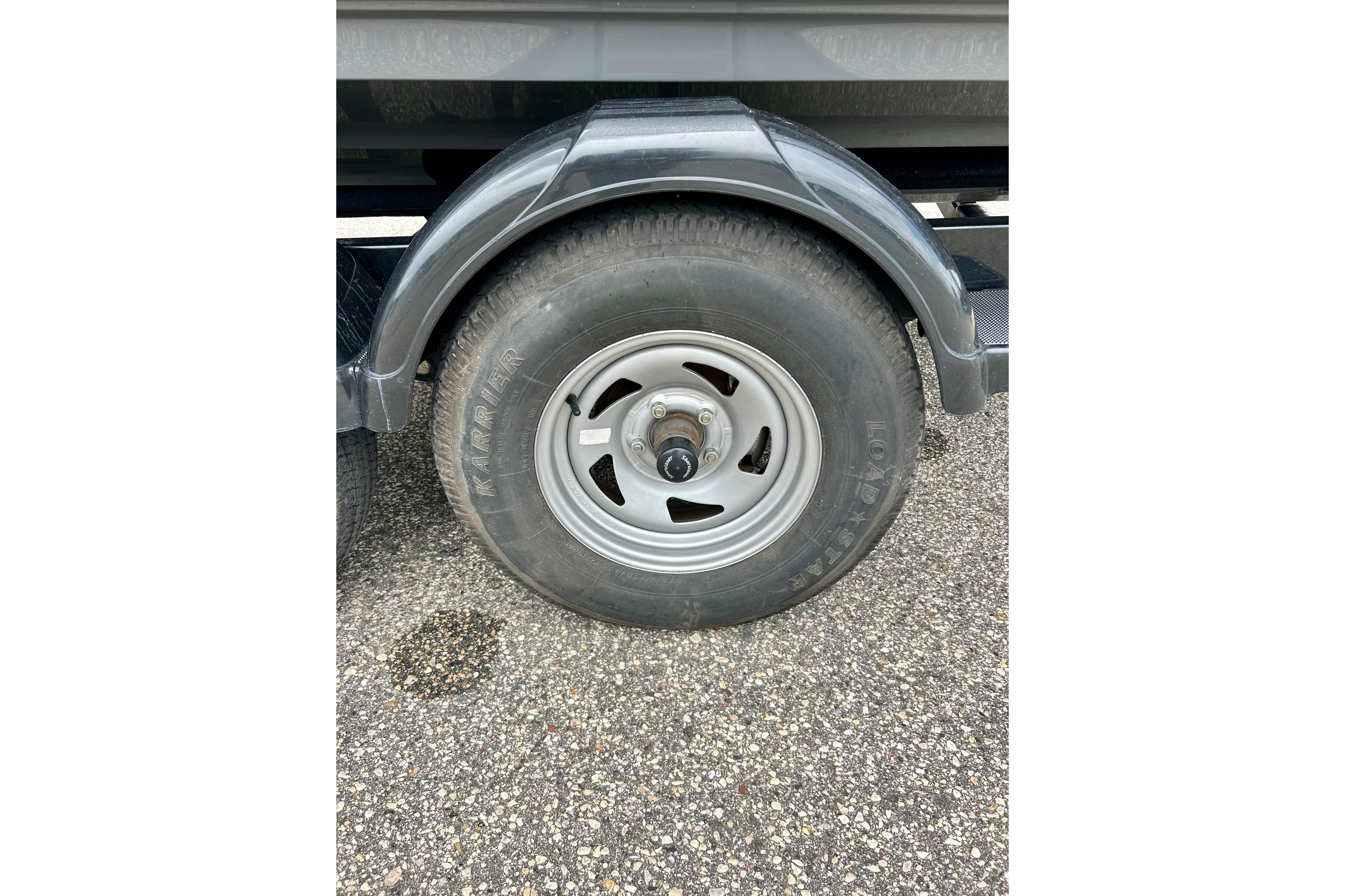 Trailer wheel of a 2015 Yamaha Boats AR210 on asphalt surface.