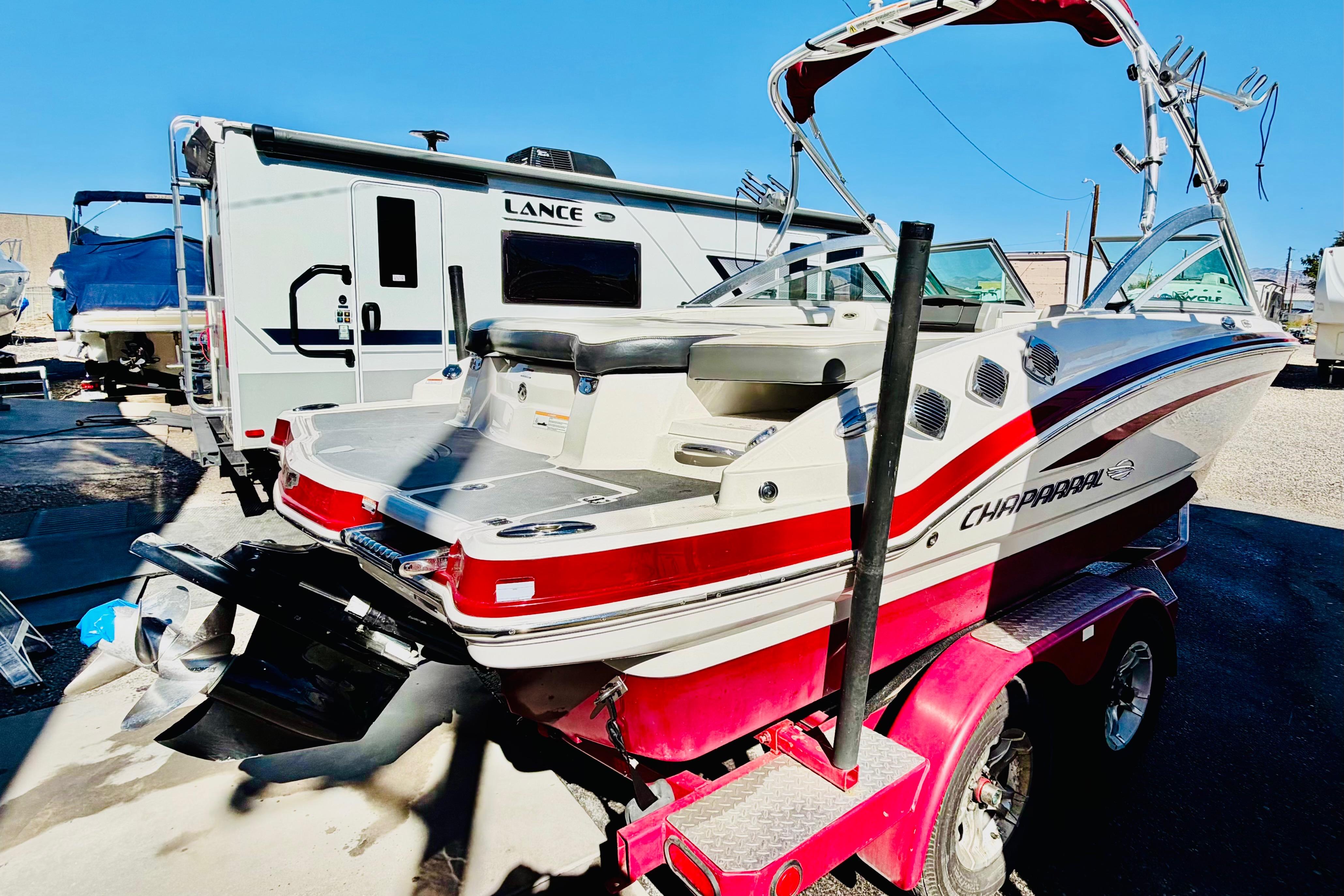 2013 Chaparral 206 SSi boat on a trailer, parked near a camper.