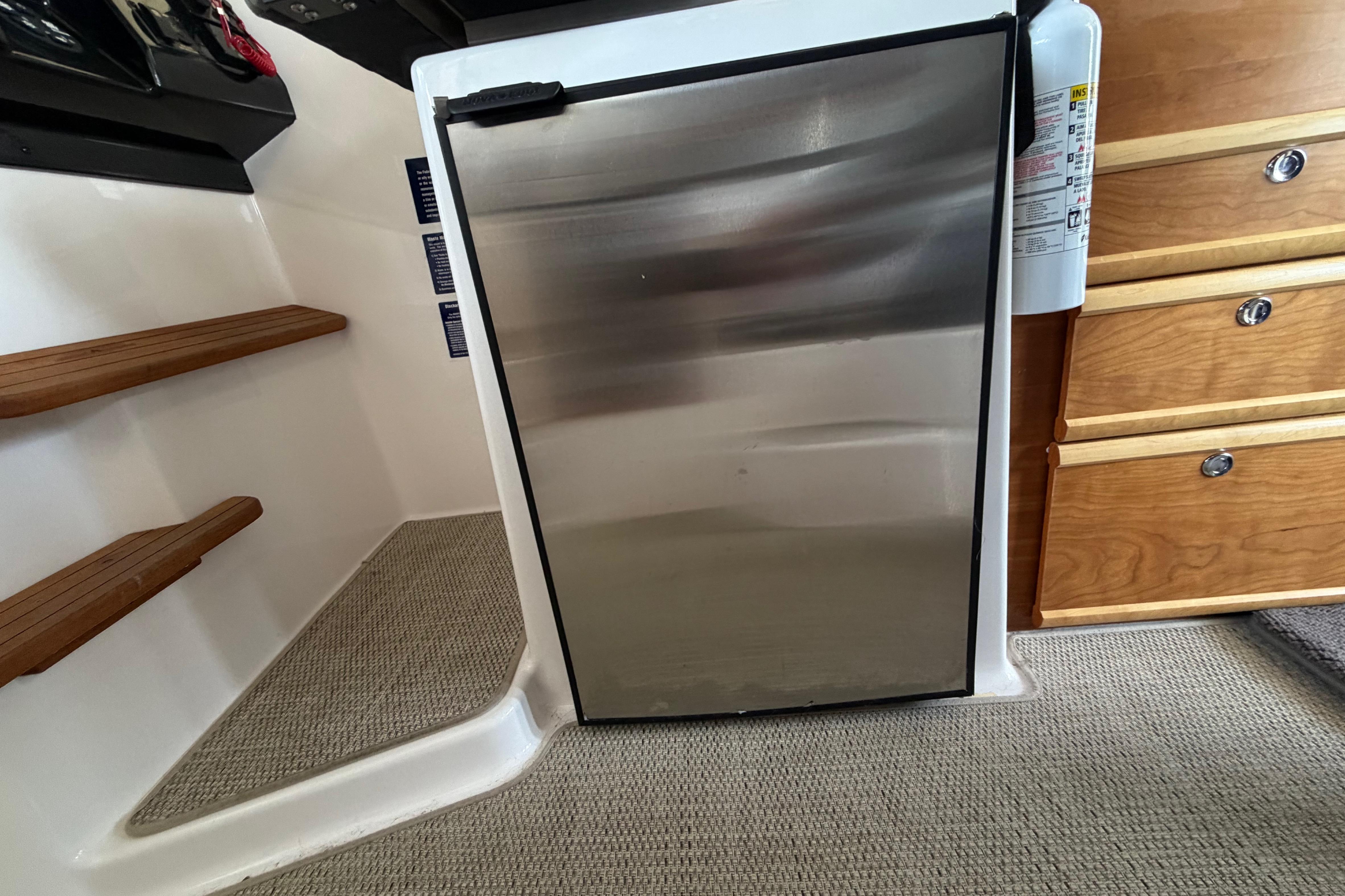 Interior of 2023 Cutwater C-288 Coupe featuring a compact stainless steel refrigerator.