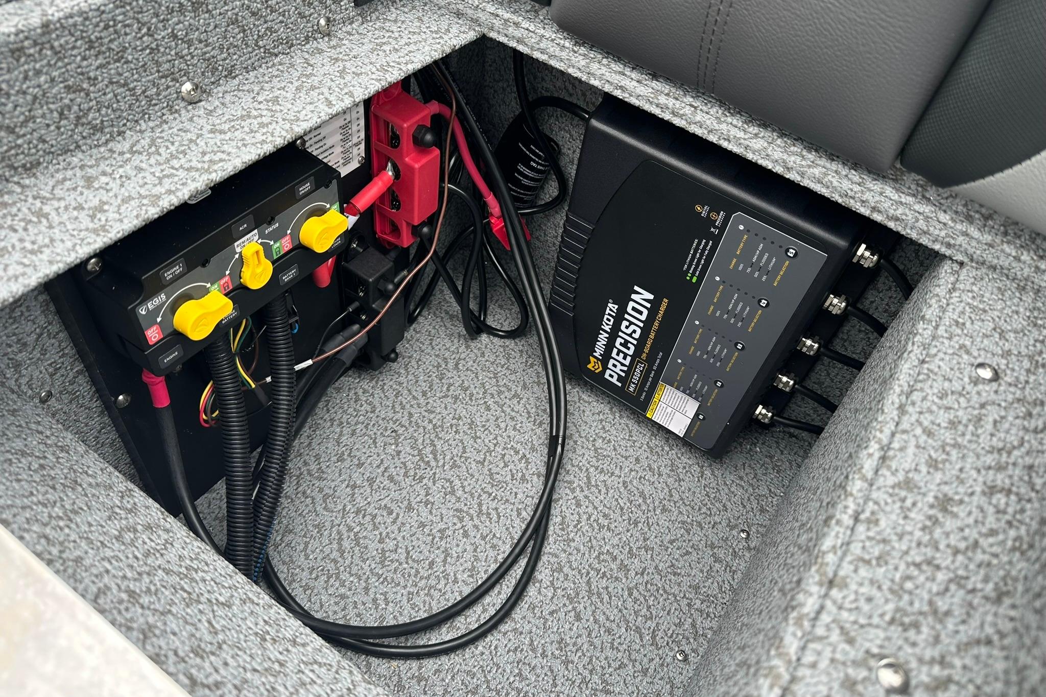 2026 Lund 1875 Impact XS SS boat battery compartment with Minn Kota Precision charger.