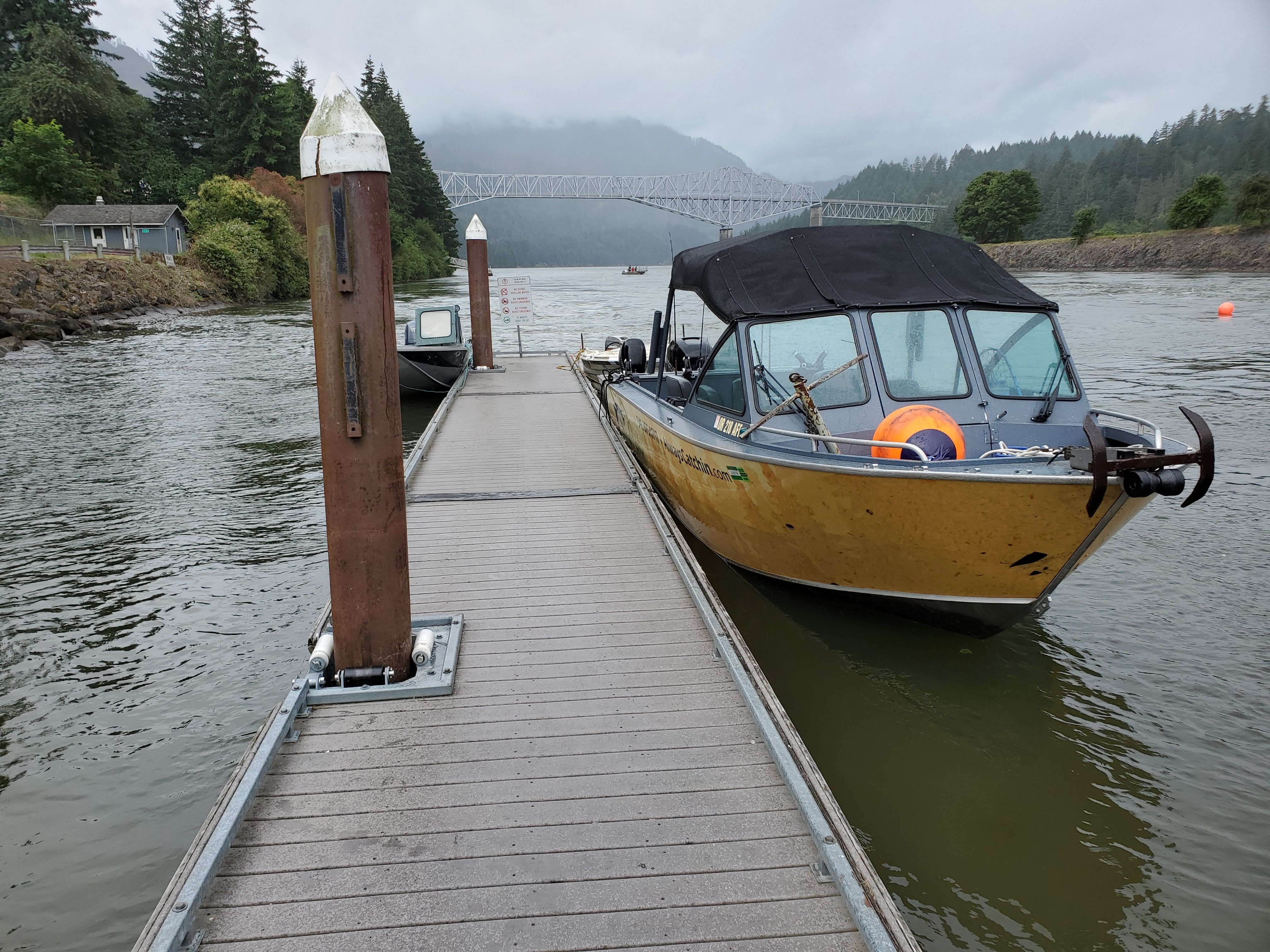 A 2015 Alumaweld Formula Vee Outboard 24 docked in a wooded river setting.
