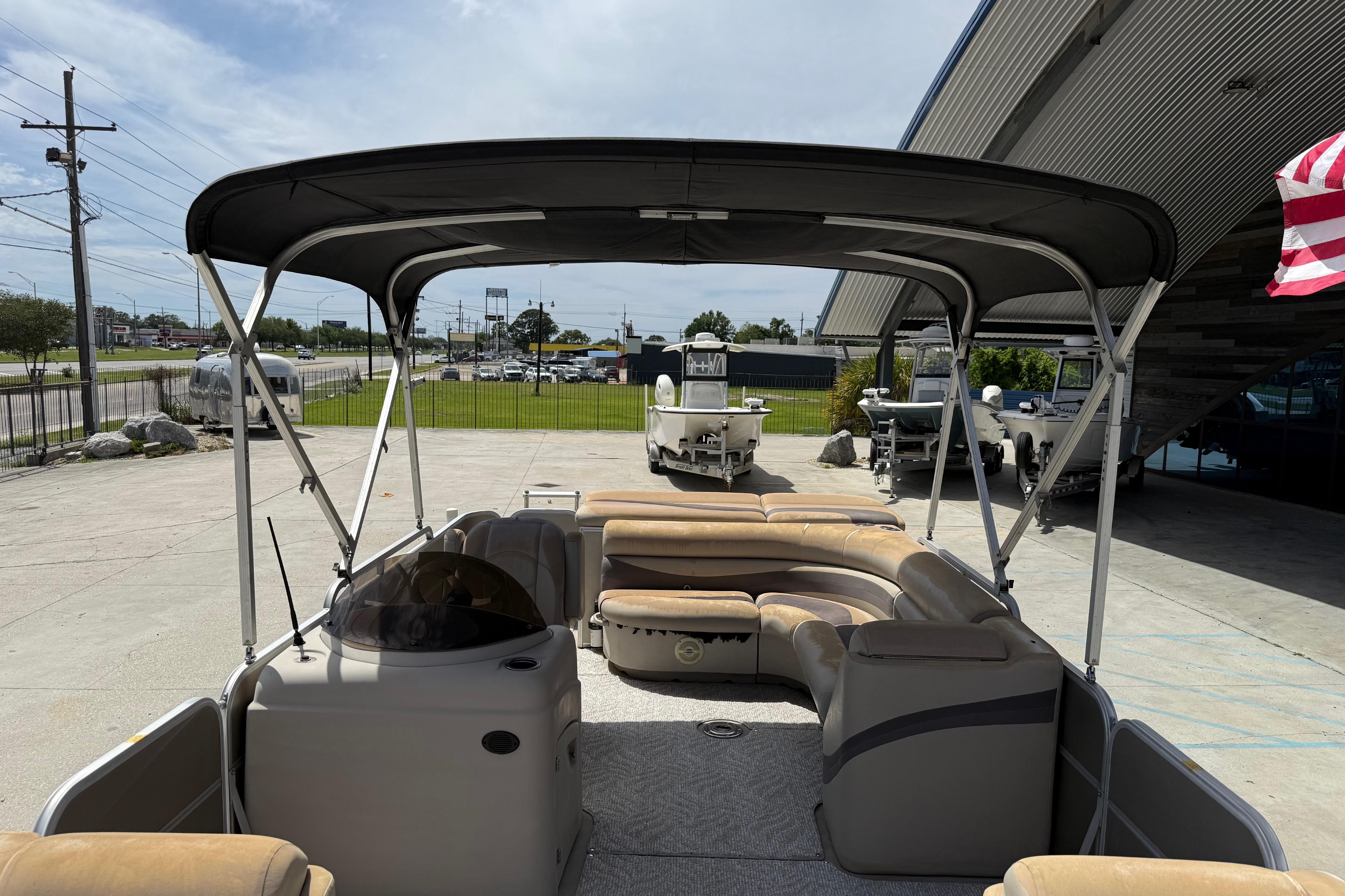 2012 South Bay 522 CR pontoon boat with canopy, parked outdoors near dealership.