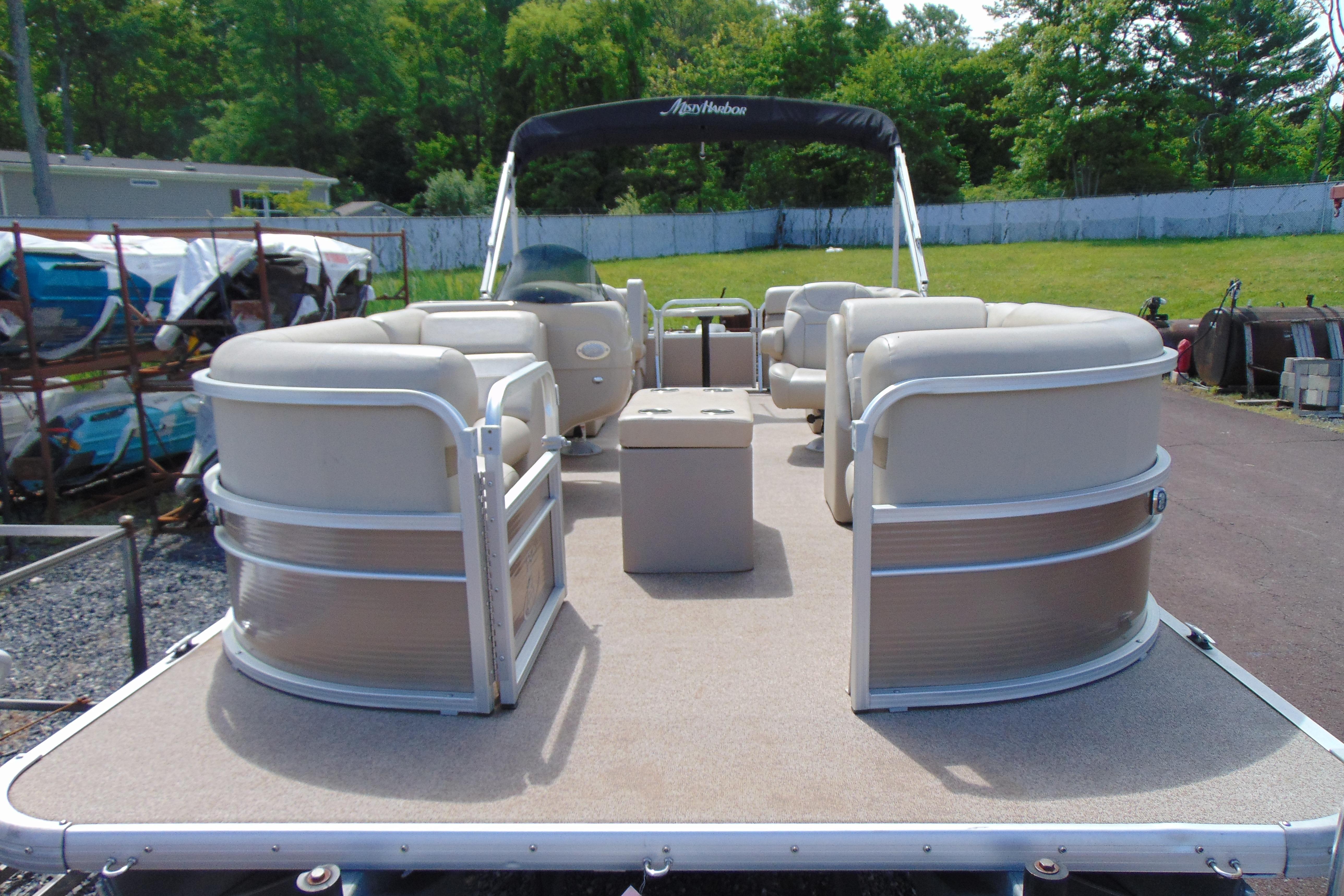 2016 Misty Harbor 245 Adventure CU pontoon boat with beige seating, parked outdoors.