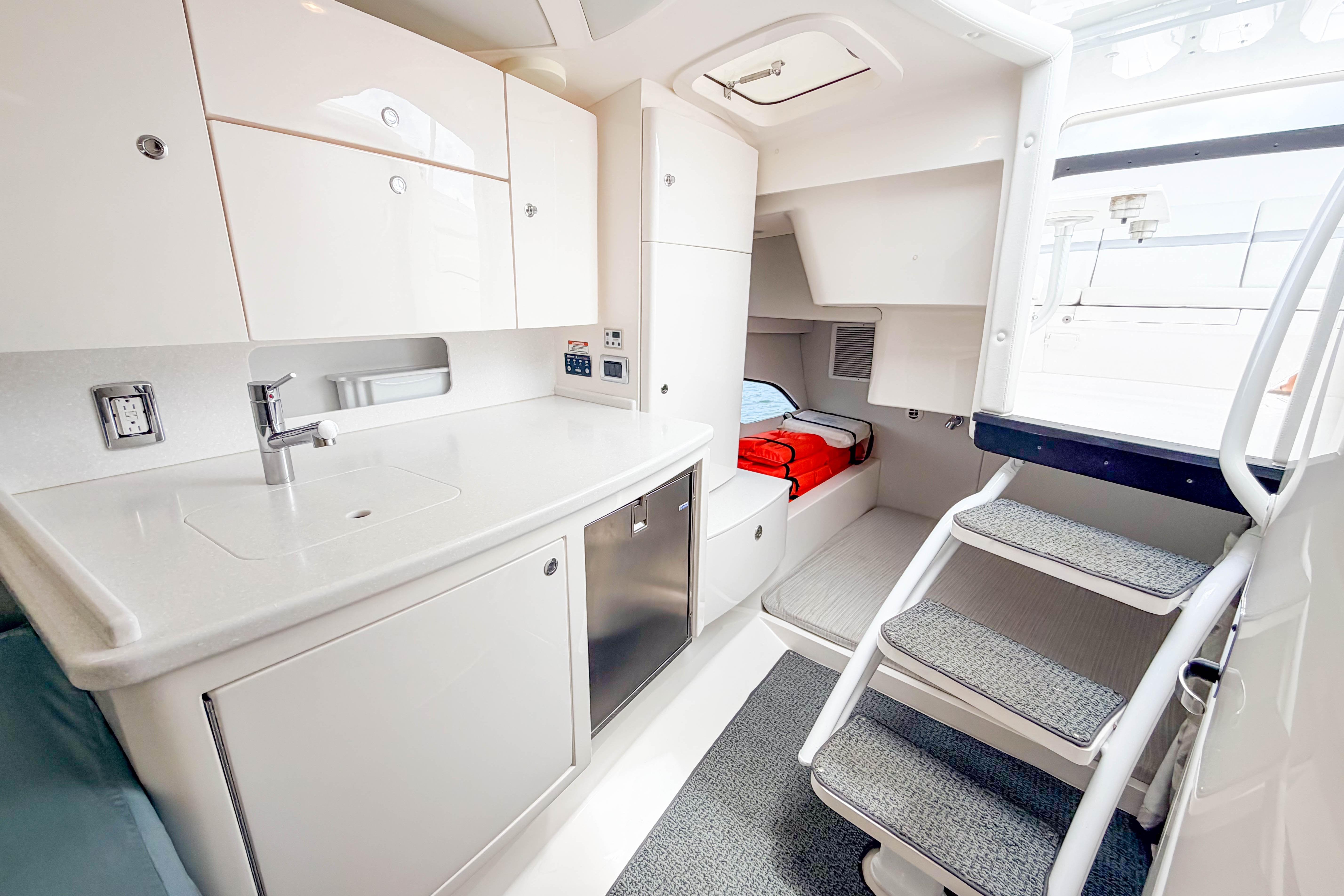 Luxurious interior of 2021 Intrepid 409 Valor boat featuring modern kitchenette and cozy sleeping area.