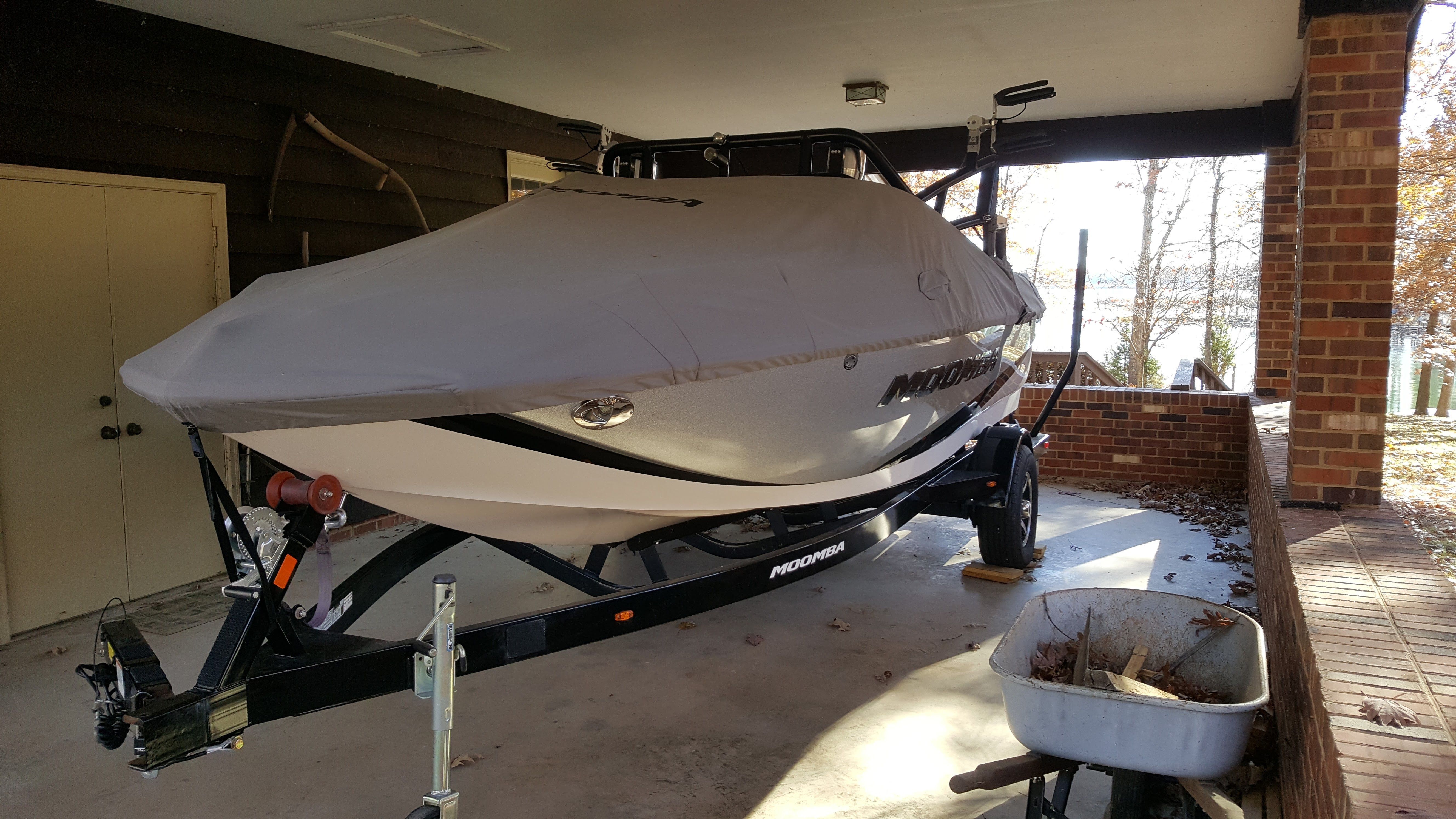 A 2016 Moomba Mondo boat on a trailer, covered and parked under a carport.