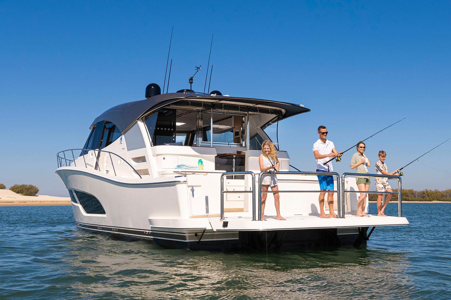 Manufacturer Provided Image: 2025 Riviera 585 SUV yacht with people fishing on deck in sunny waters.