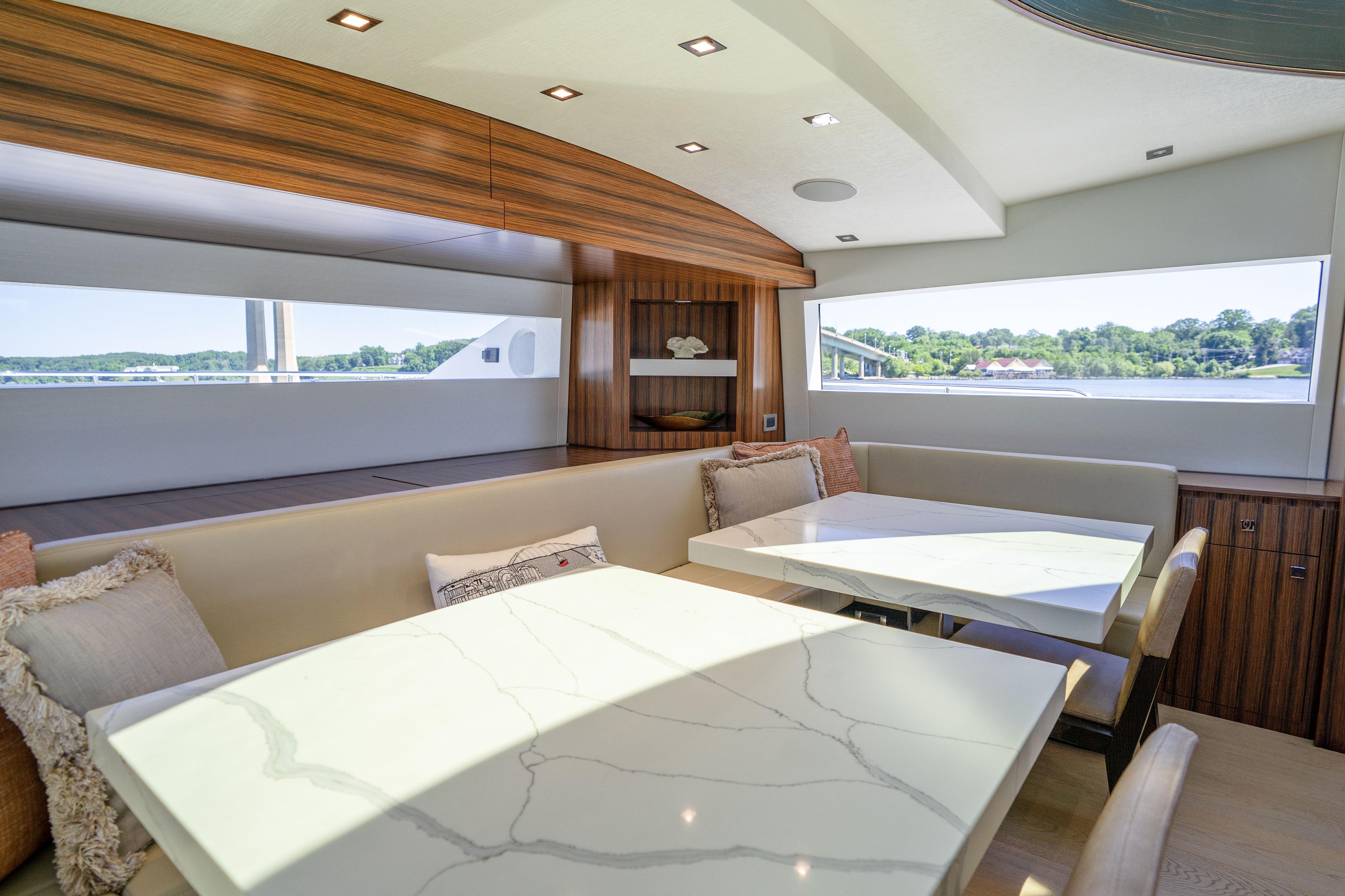 Luxurious interior of 2021 Hatteras M75 Panacera yacht with elegant dining area and scenic views.
