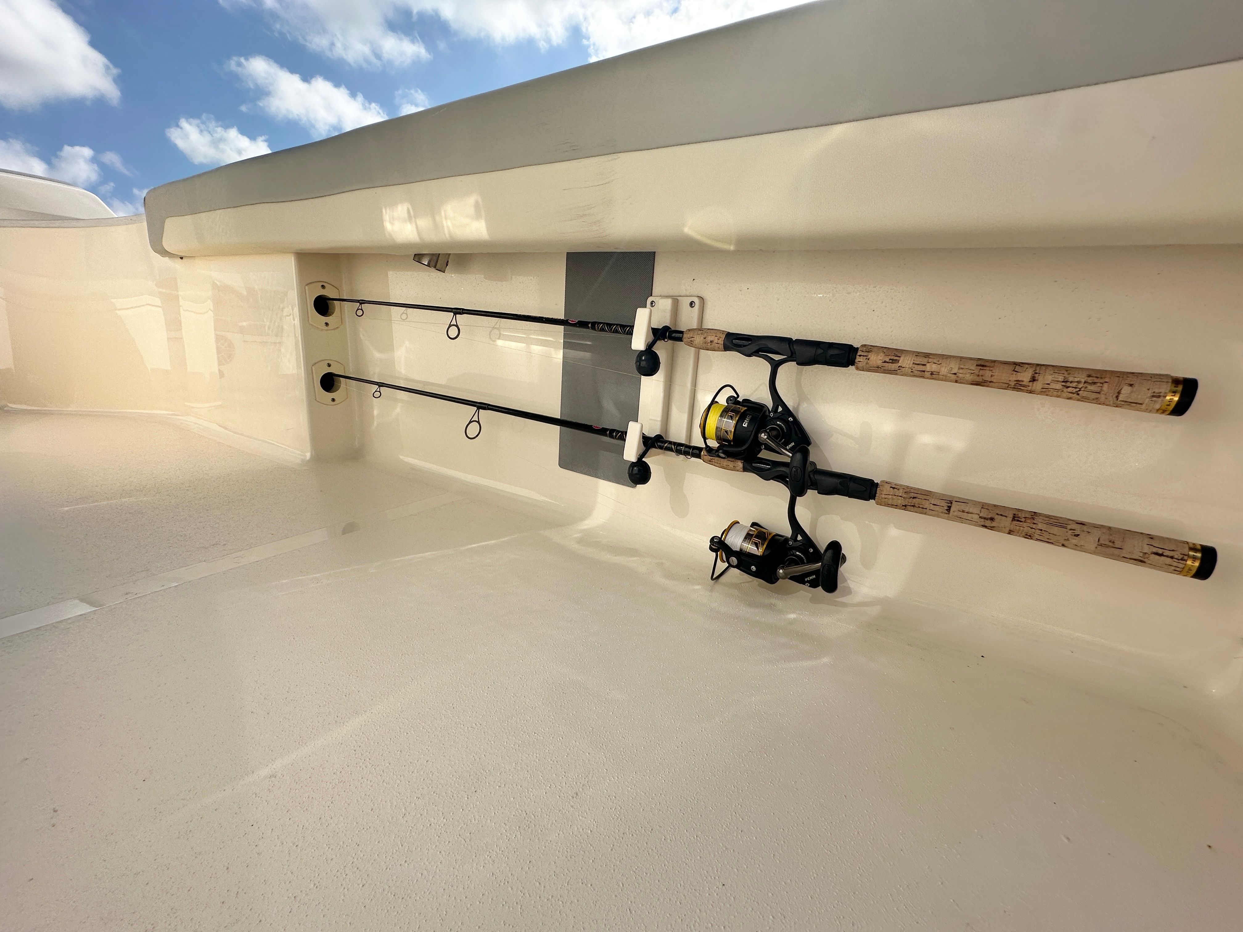 Fishing rods stored in a boat compartment under a blue sky.