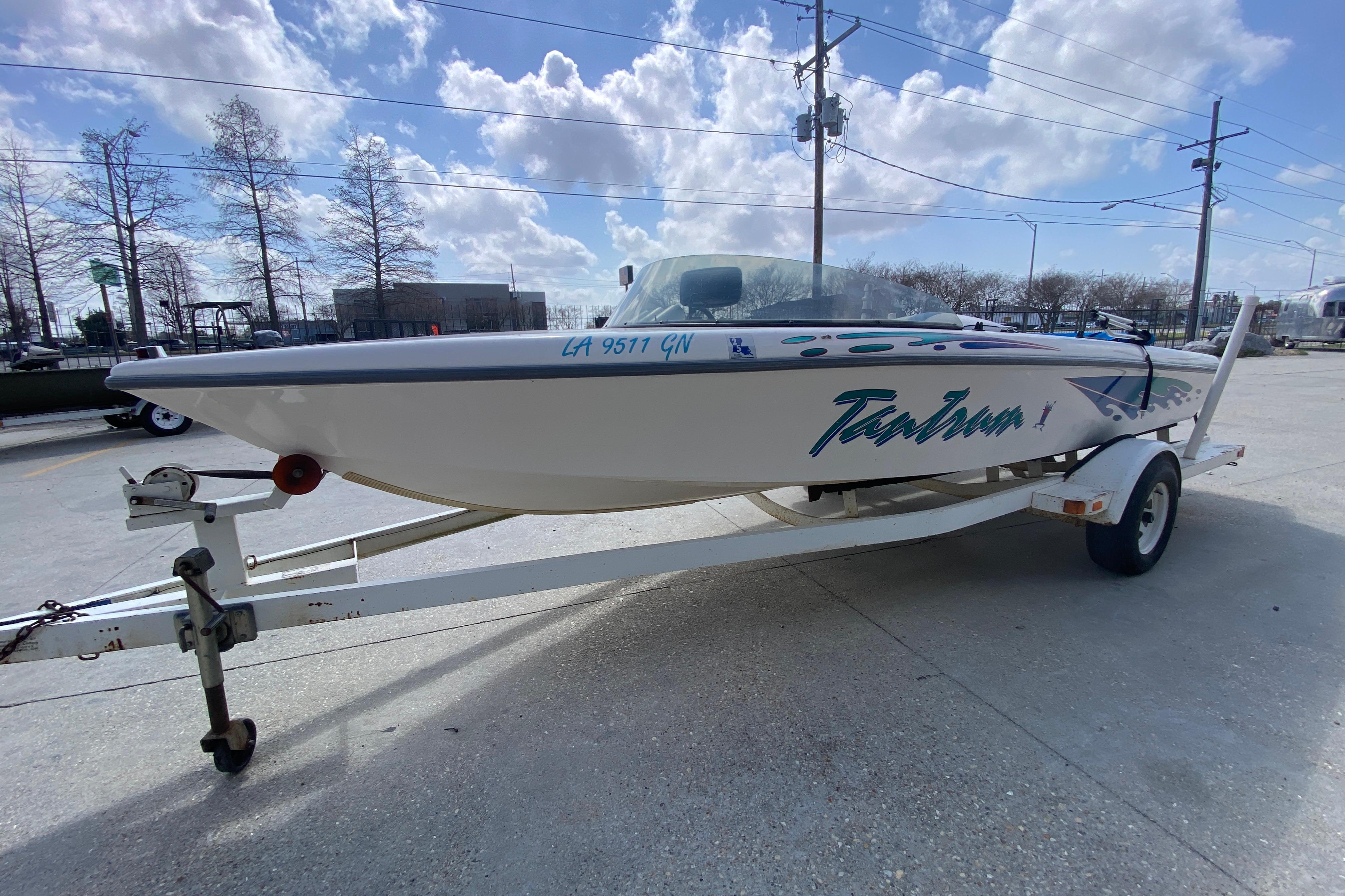 1997 Malibu Tantrum boat on trailer under a partly cloudy sky.