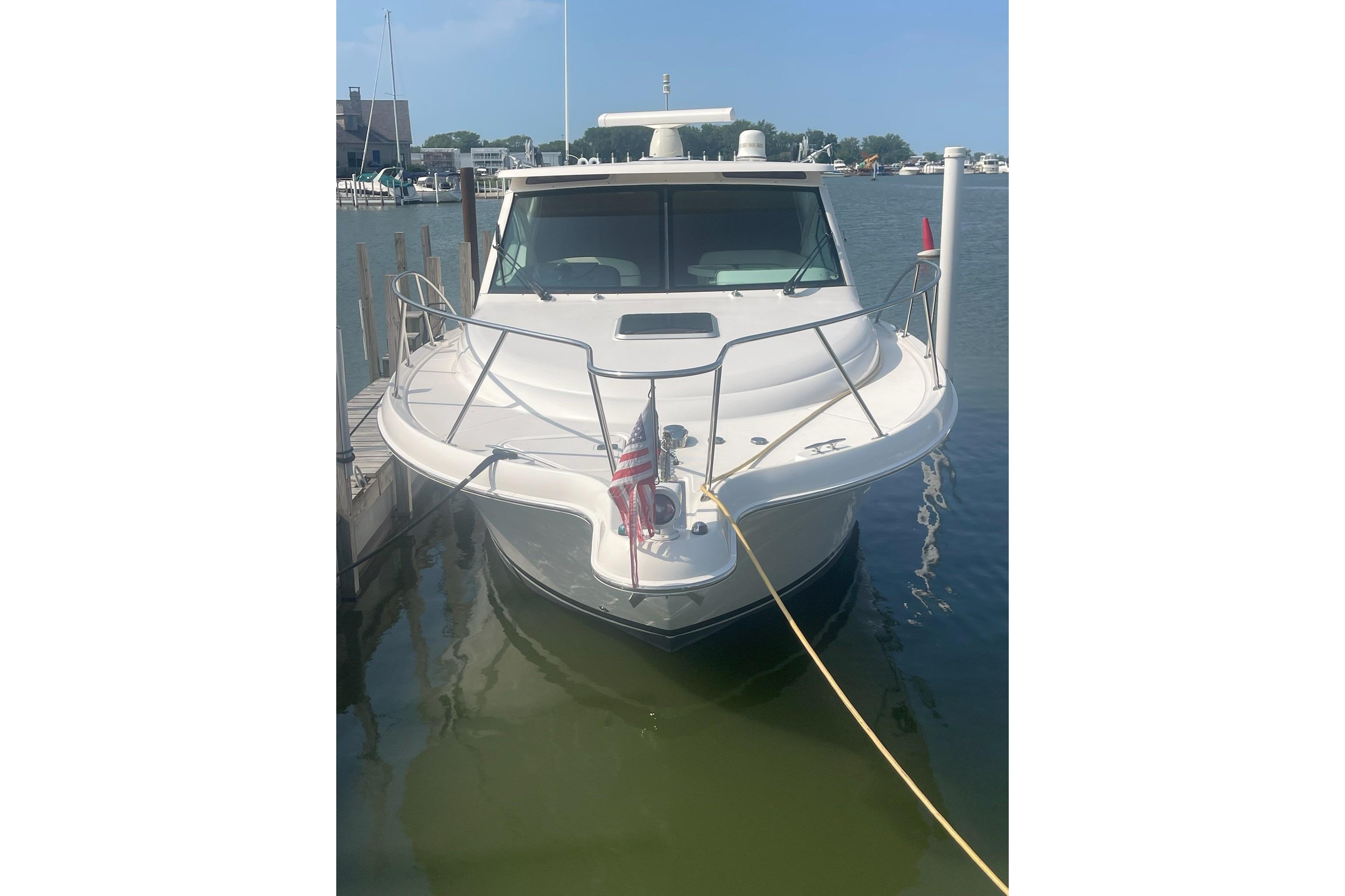 2013 Tiara Yachts 3100 Open docked, front view with American flag, calm waters.