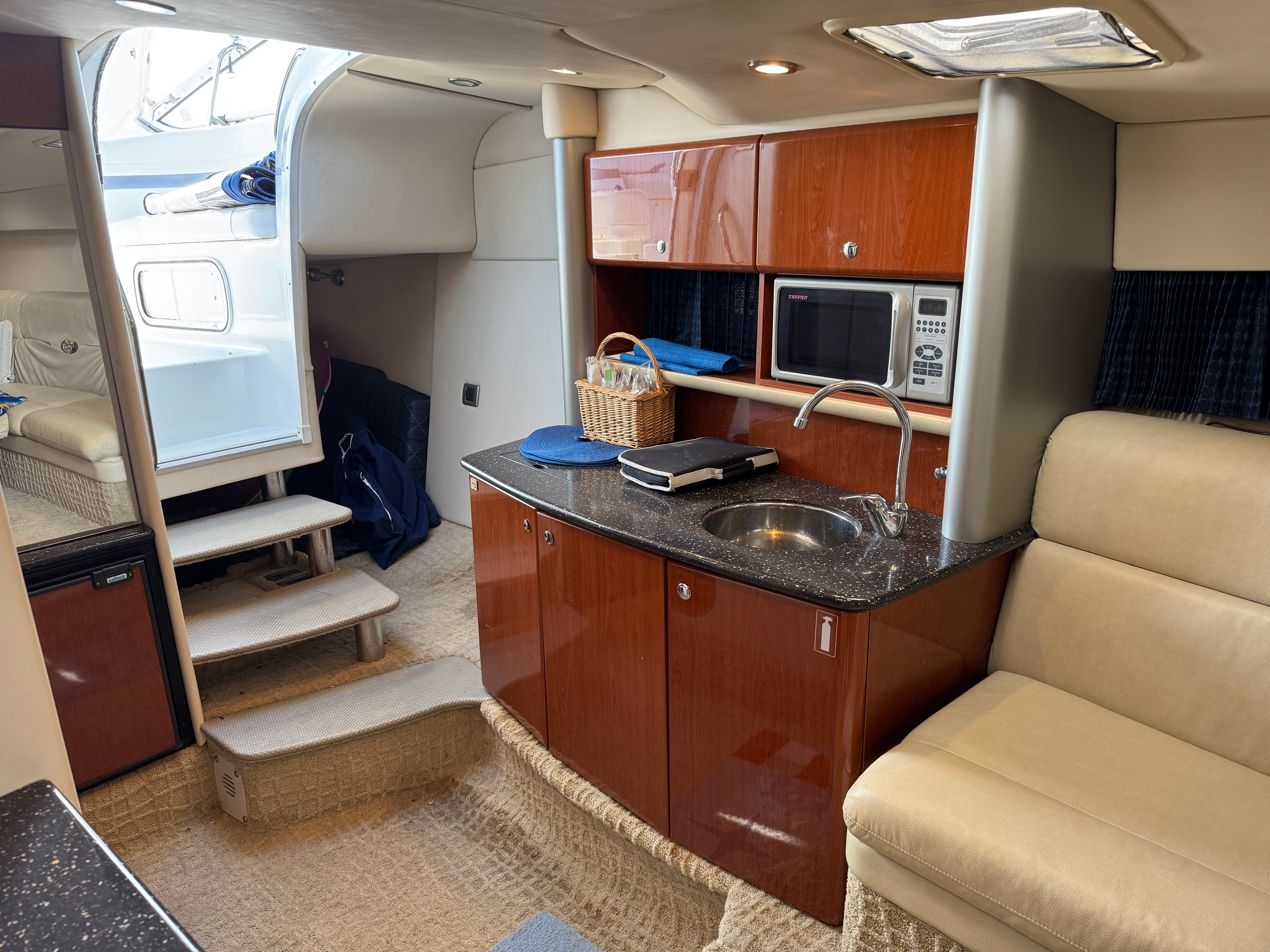 Interior of a yacht with kitchenette, microwave, and seating area.