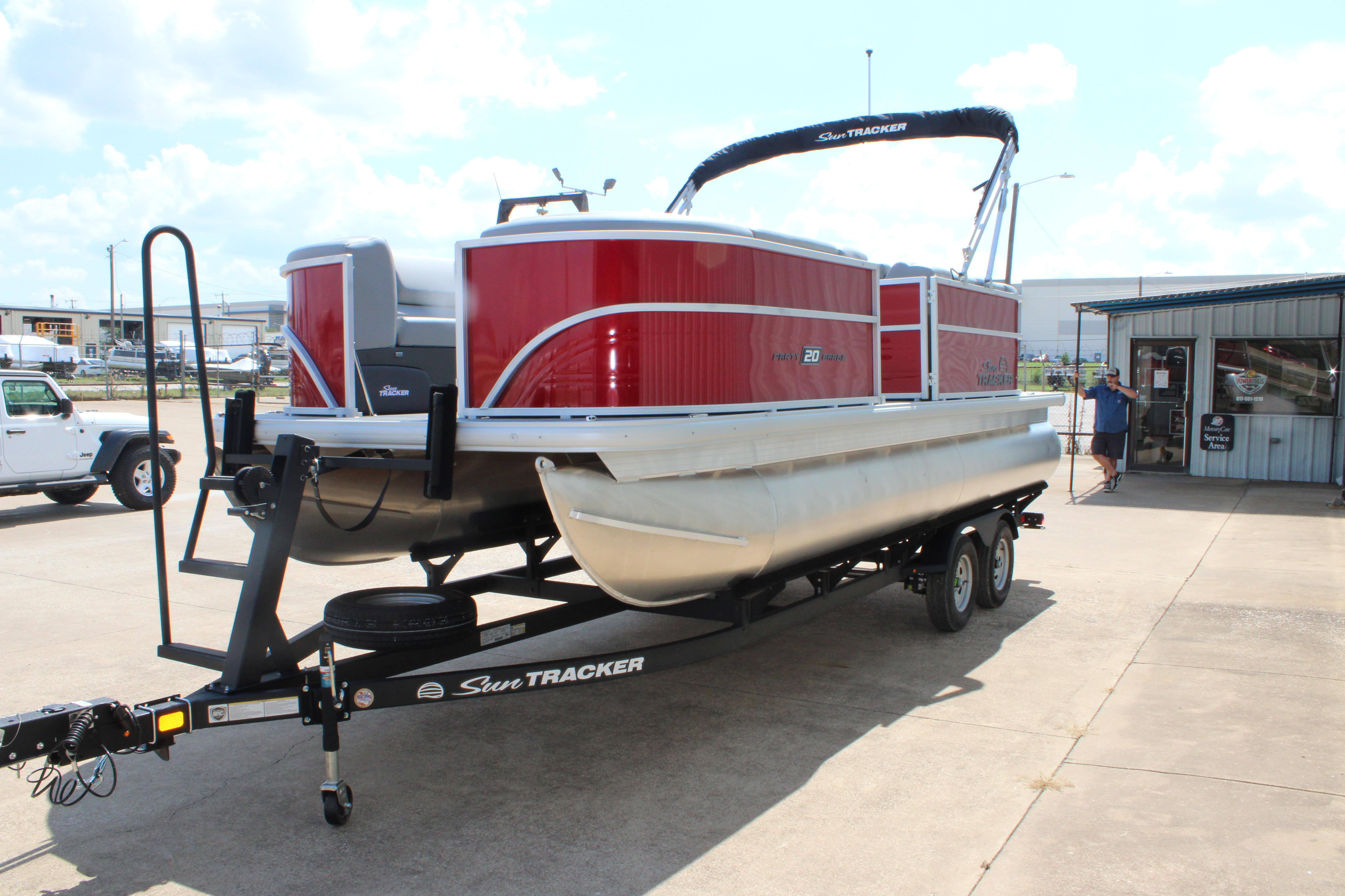 2026 Sun Tracker Party Barge 20 DLX pontoon boat on trailer, parked outdoors.