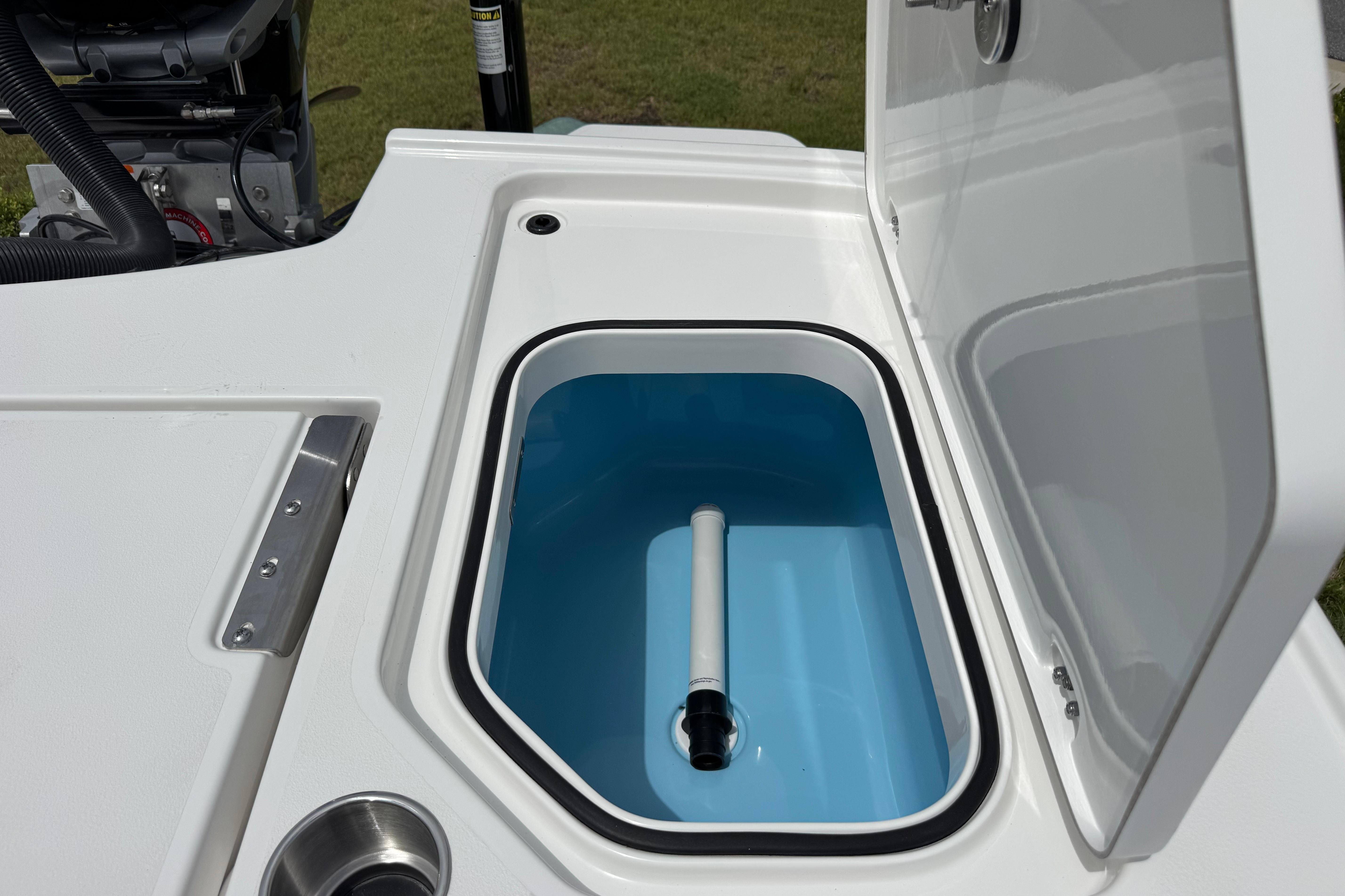 Open storage compartment on 2027 Caymas 26 HB boat, featuring a blue interior and white exterior.