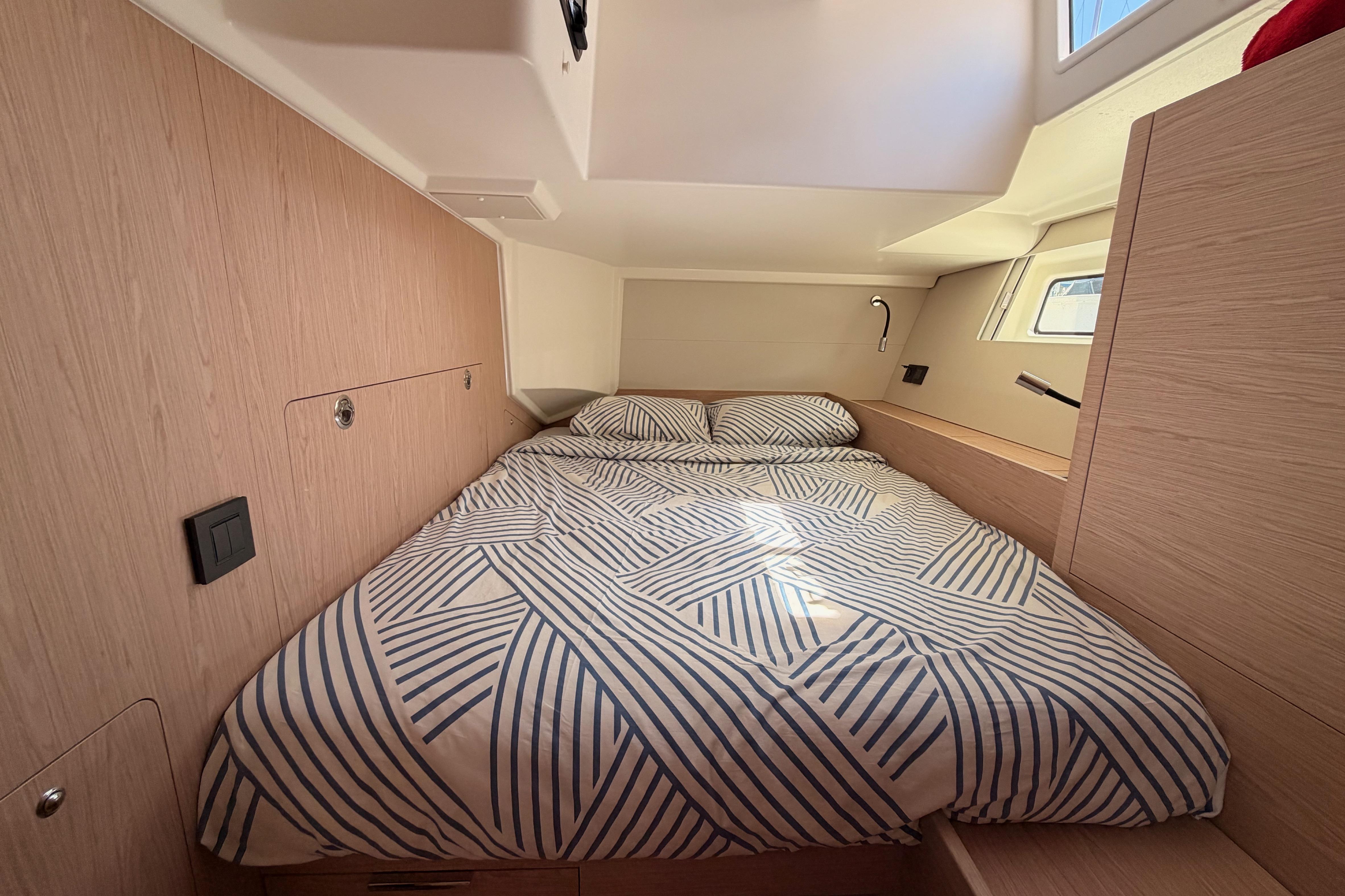 Cozy cabin interior of 2022 Beneteau Oceanis Yacht 54 with striped bedding.