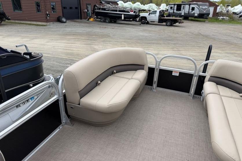 2025 Sun Tracker Party Barge 16 DLX interior with beige seating, parked outdoors.