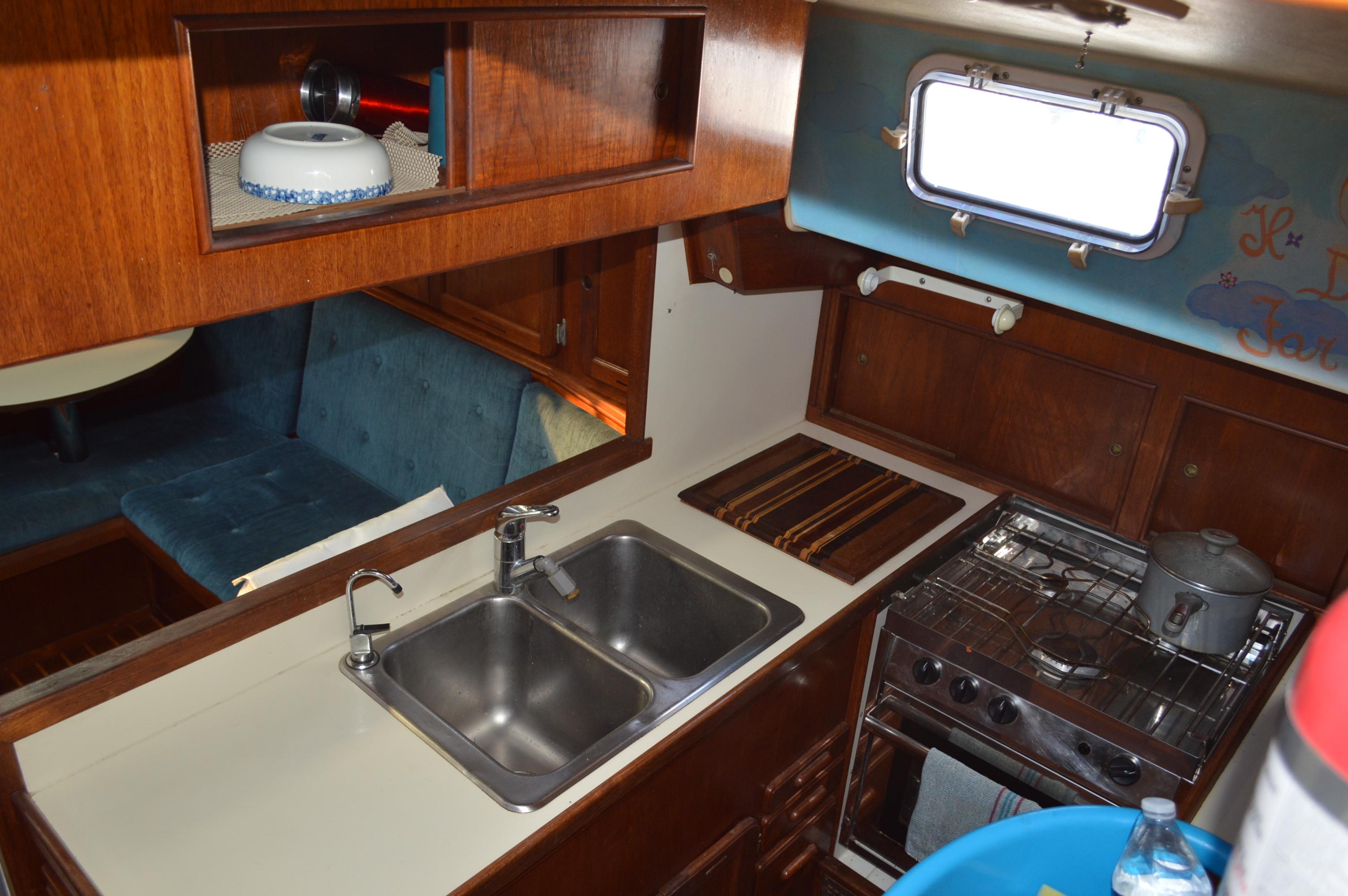 1979 Morgan 461 yacht interior kitchen with sink, stove, and wooden cabinetry.