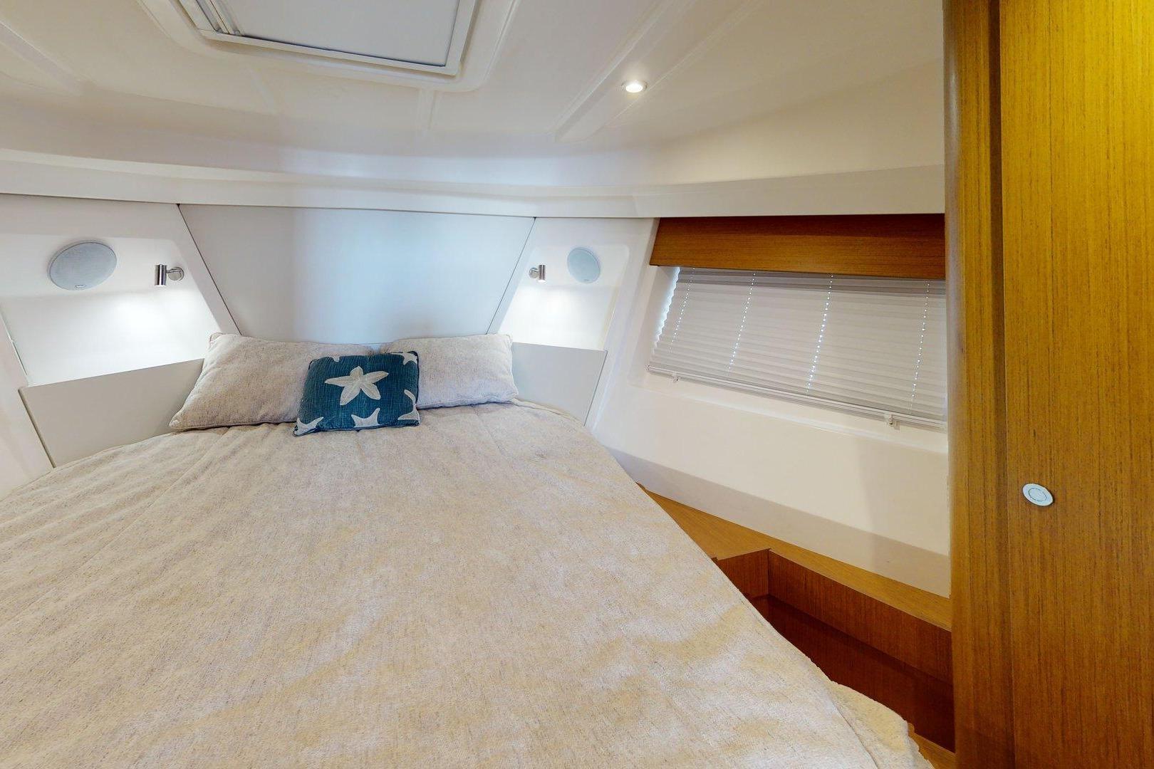 Cozy bedroom interior of 2021 Beneteau Swift Trawler 35 with starfish-themed pillow.