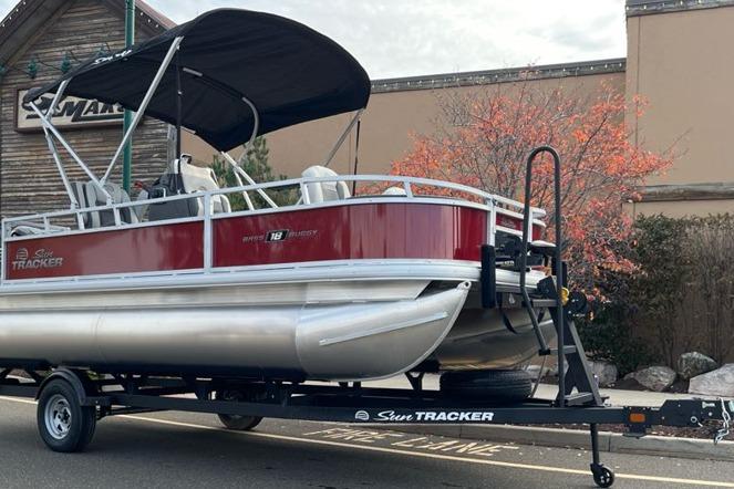 2026 Sun Tracker Bass Buggy 18 DLX pontoon boat on trailer, parked outdoors.