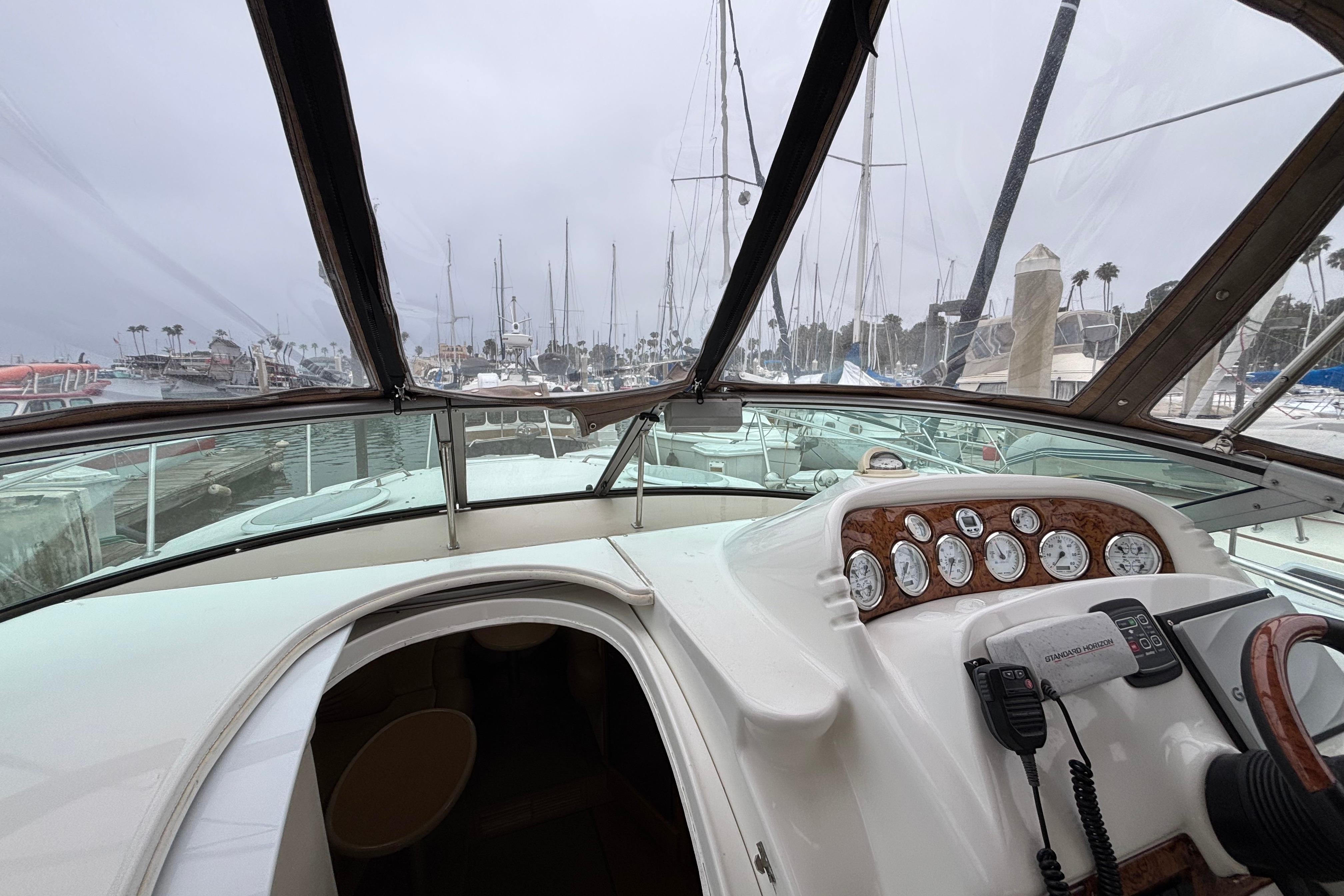 Interior view of a 2004 Larson 310 boat cockpit with marina background.