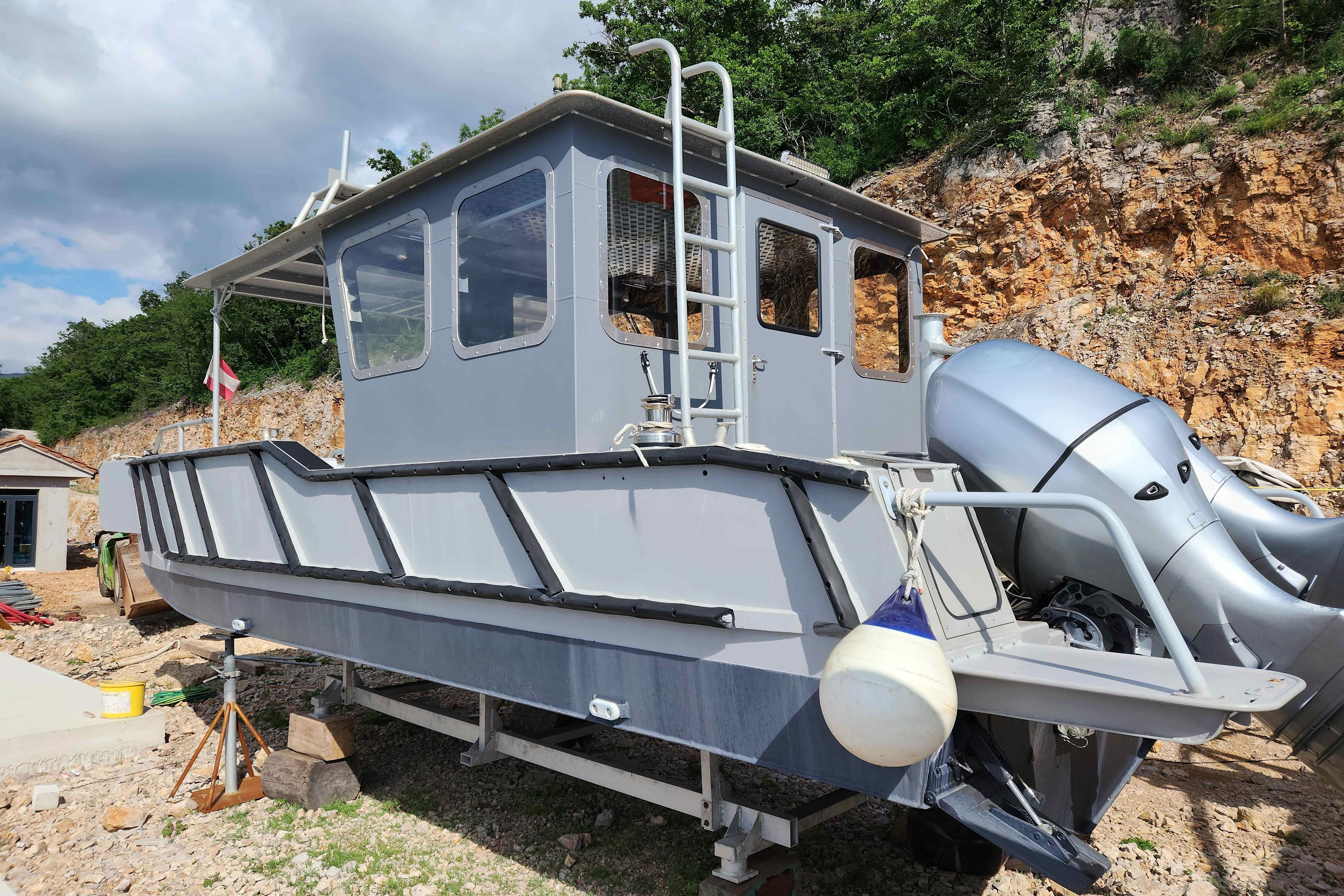 Aluminum boat ALUTEH LC 853, 2018 model, on land with rocky background.