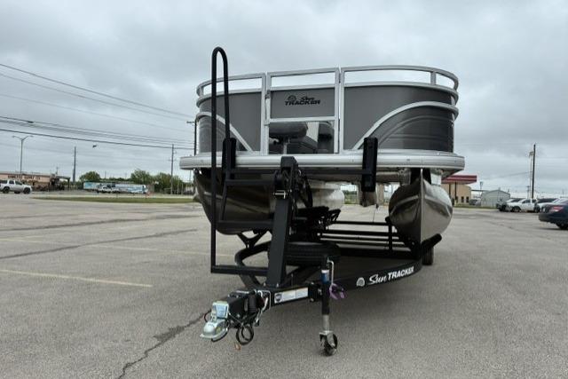 2026 Sun Tracker Fishin' Barge 22 DLX pontoon boat on trailer in parking lot.