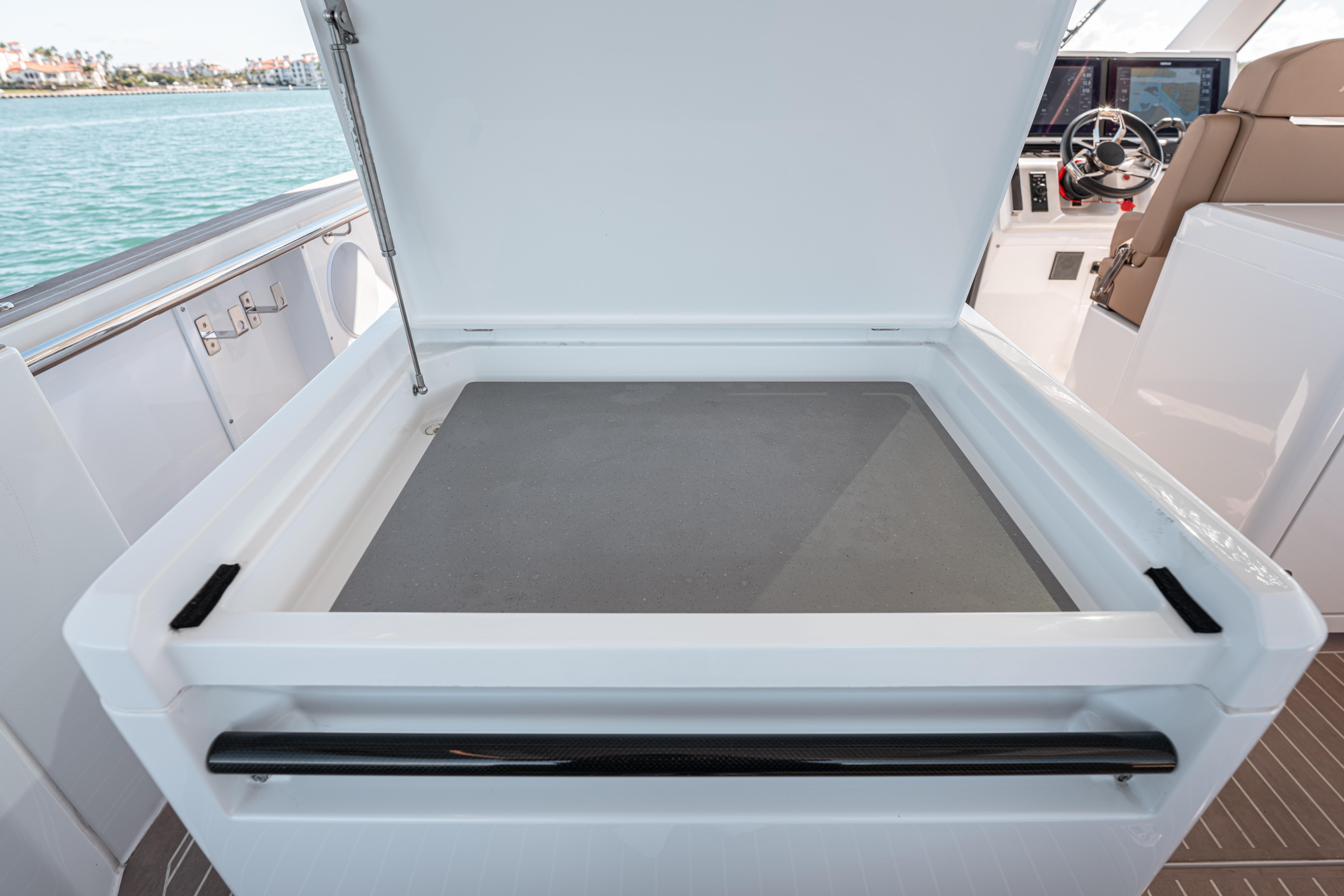 2024 Fjord Boats 53XL open storage compartment on deck, with helm in background.