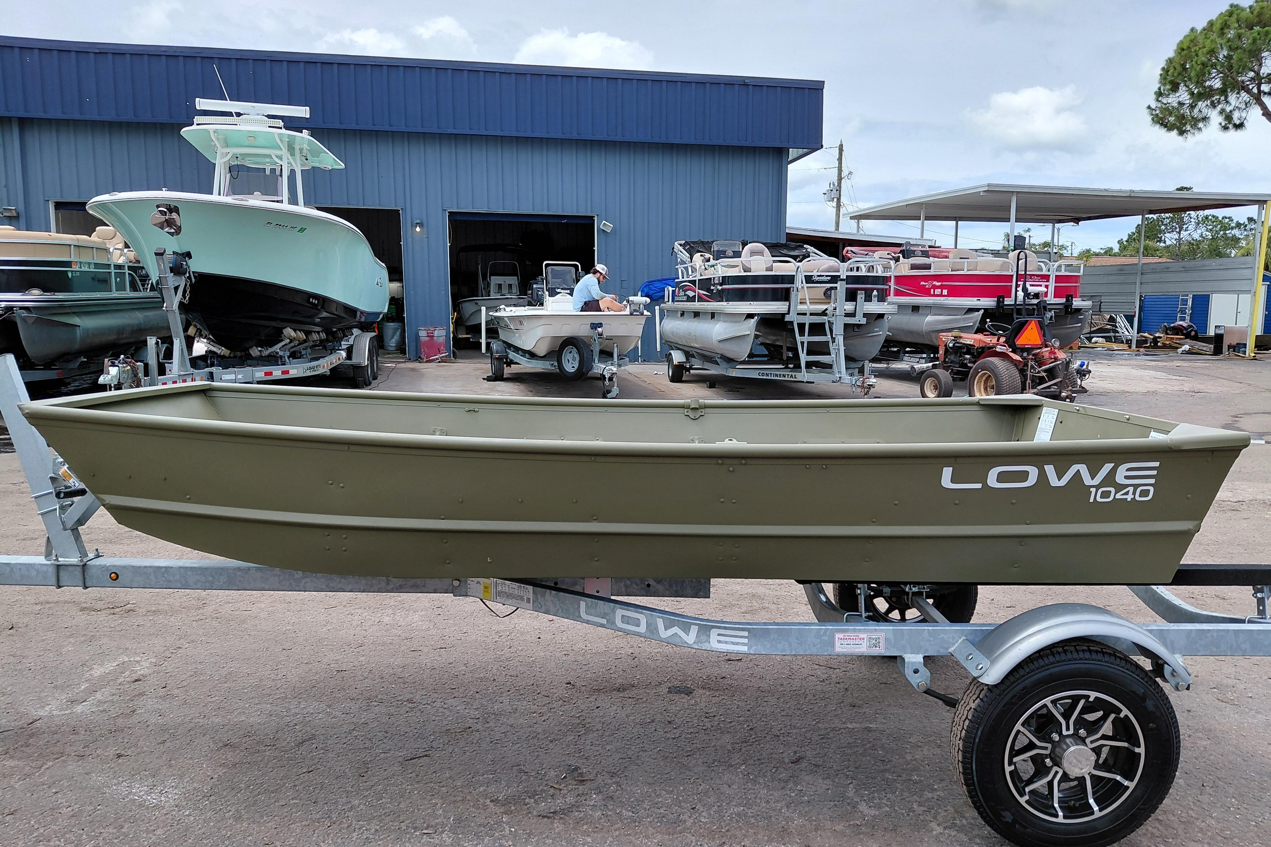 2025 Lowe L1040 Jon boat on trailer at a dealership, surrounded by other boats.