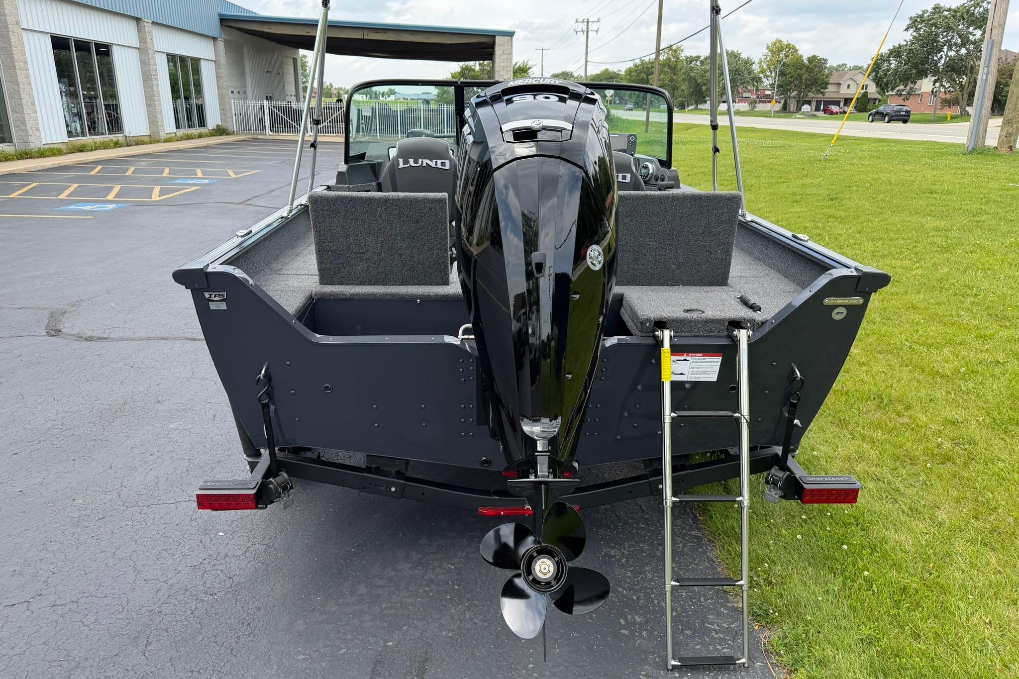 2027 Lund 1675 Adventure Sport boat with outboard motor and ladder, parked on pavement.