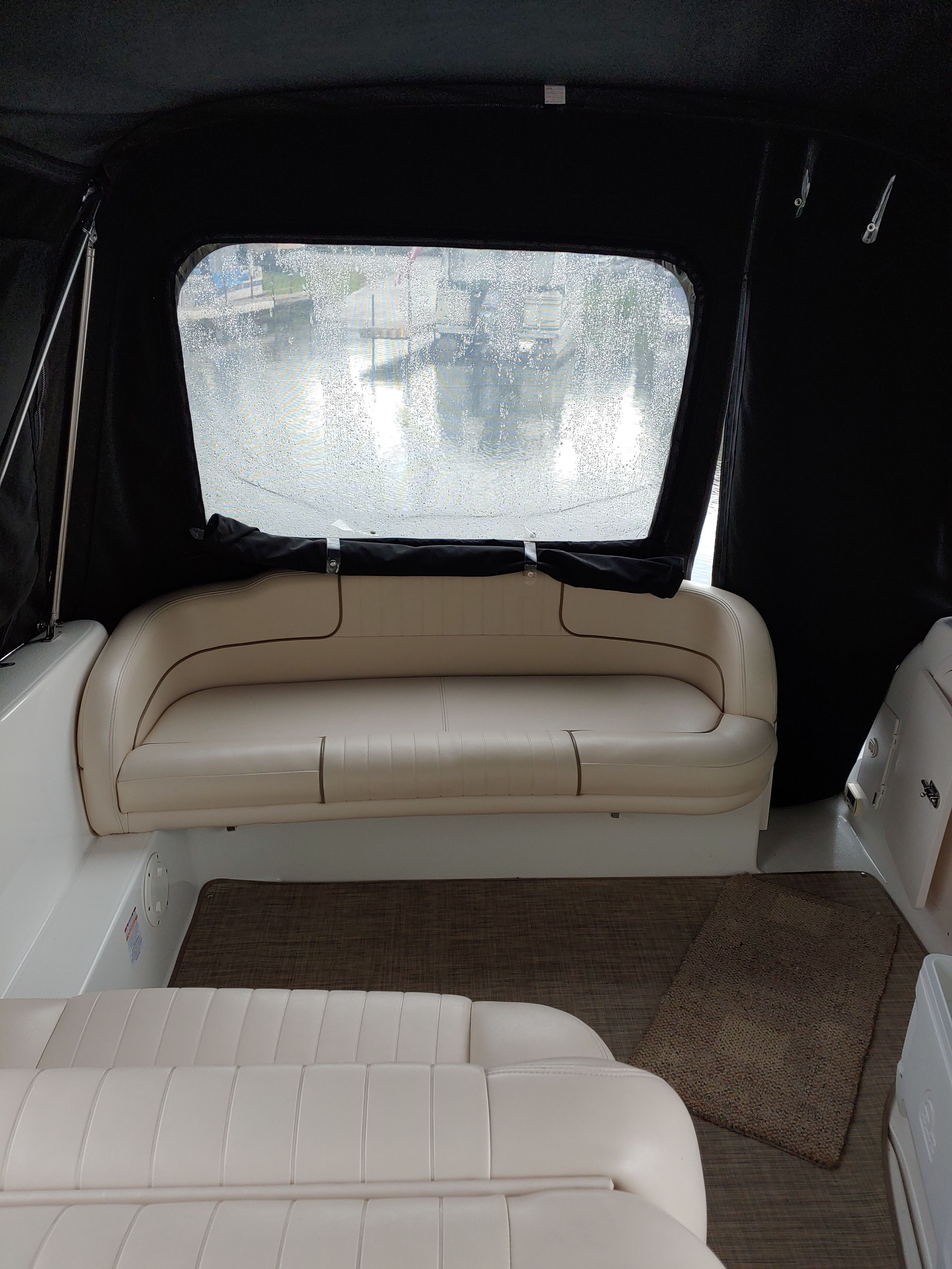 Interior of a boat with beige leather seating and carpeted floor.