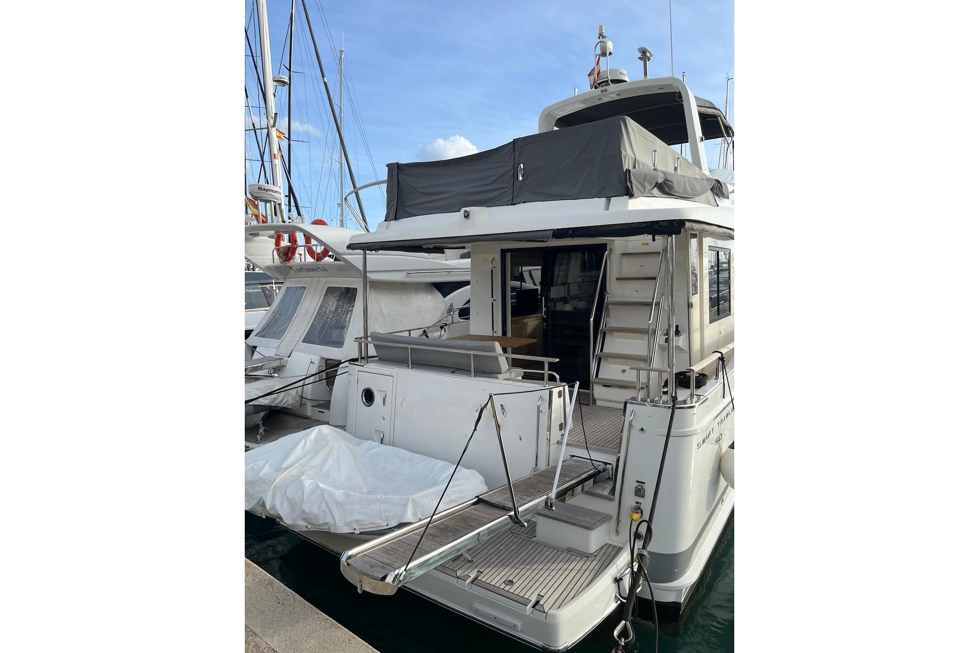 2021 Beneteau Swift Trawler 50 docked, showcasing rear deck and upper seating area.