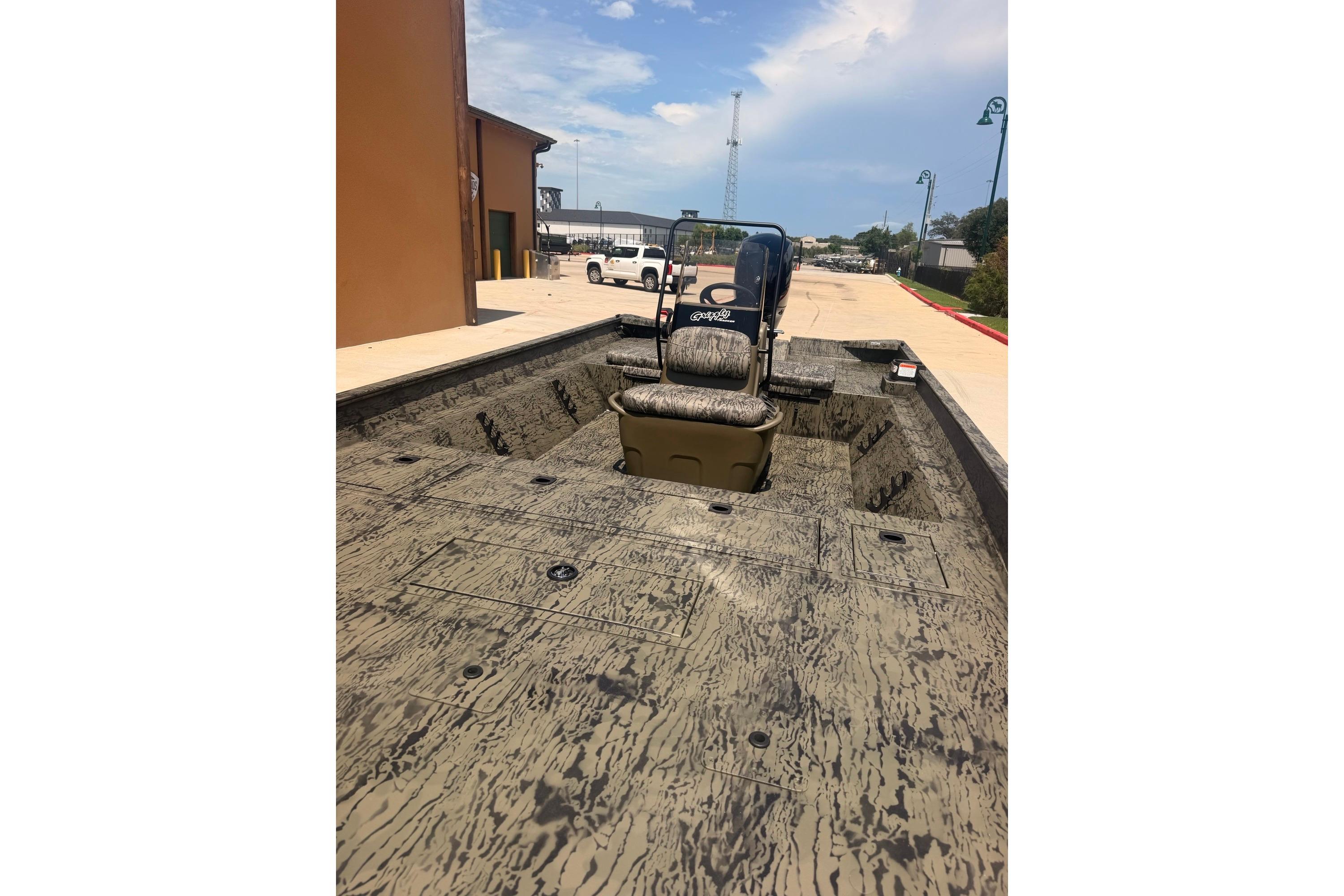 2026 Tracker Grizzly 2072 CC boat with camouflage interior, parked outdoors.