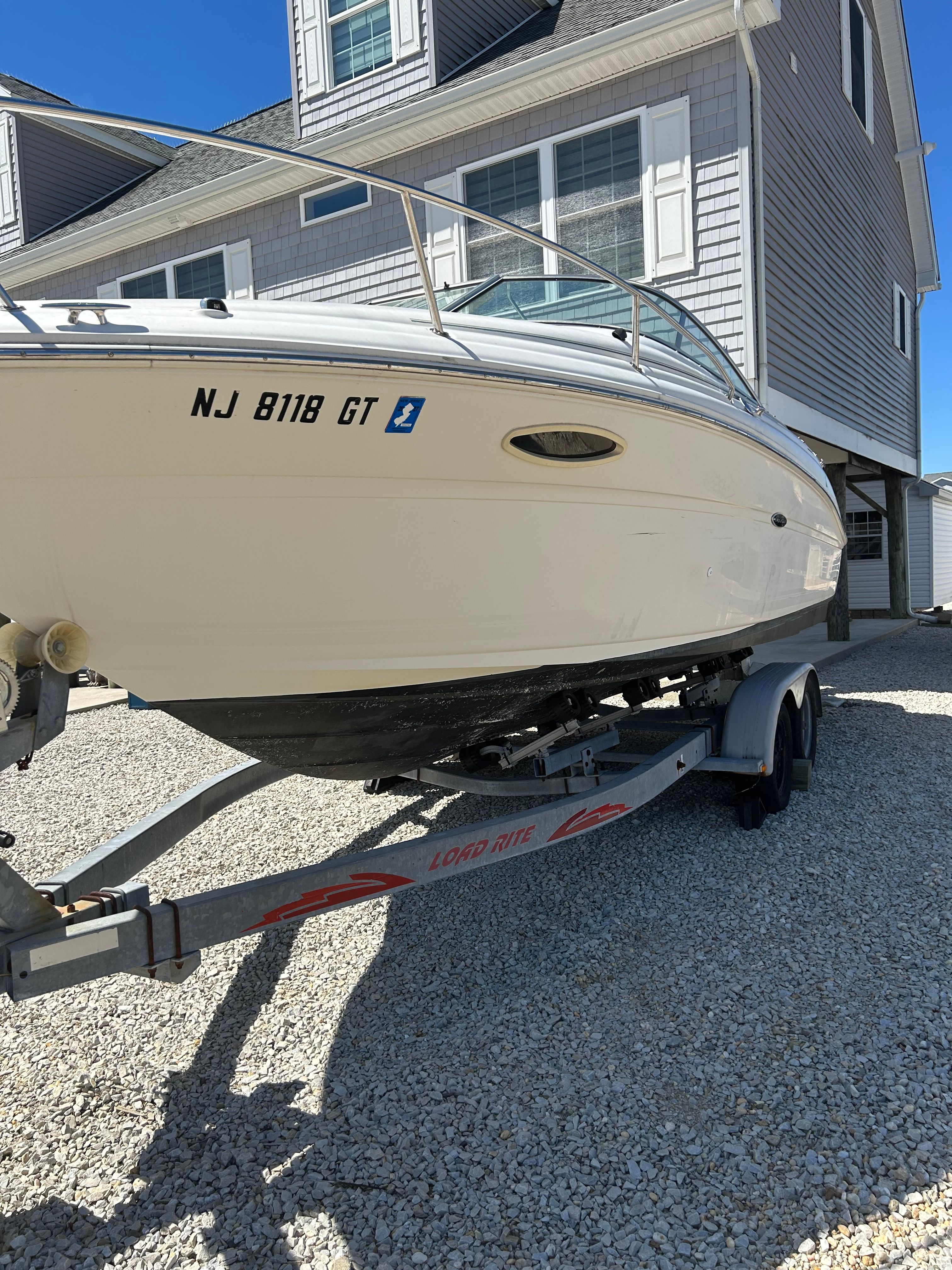 A 2002 Sea Ray 225 Weekender on a trailer in front of a house.