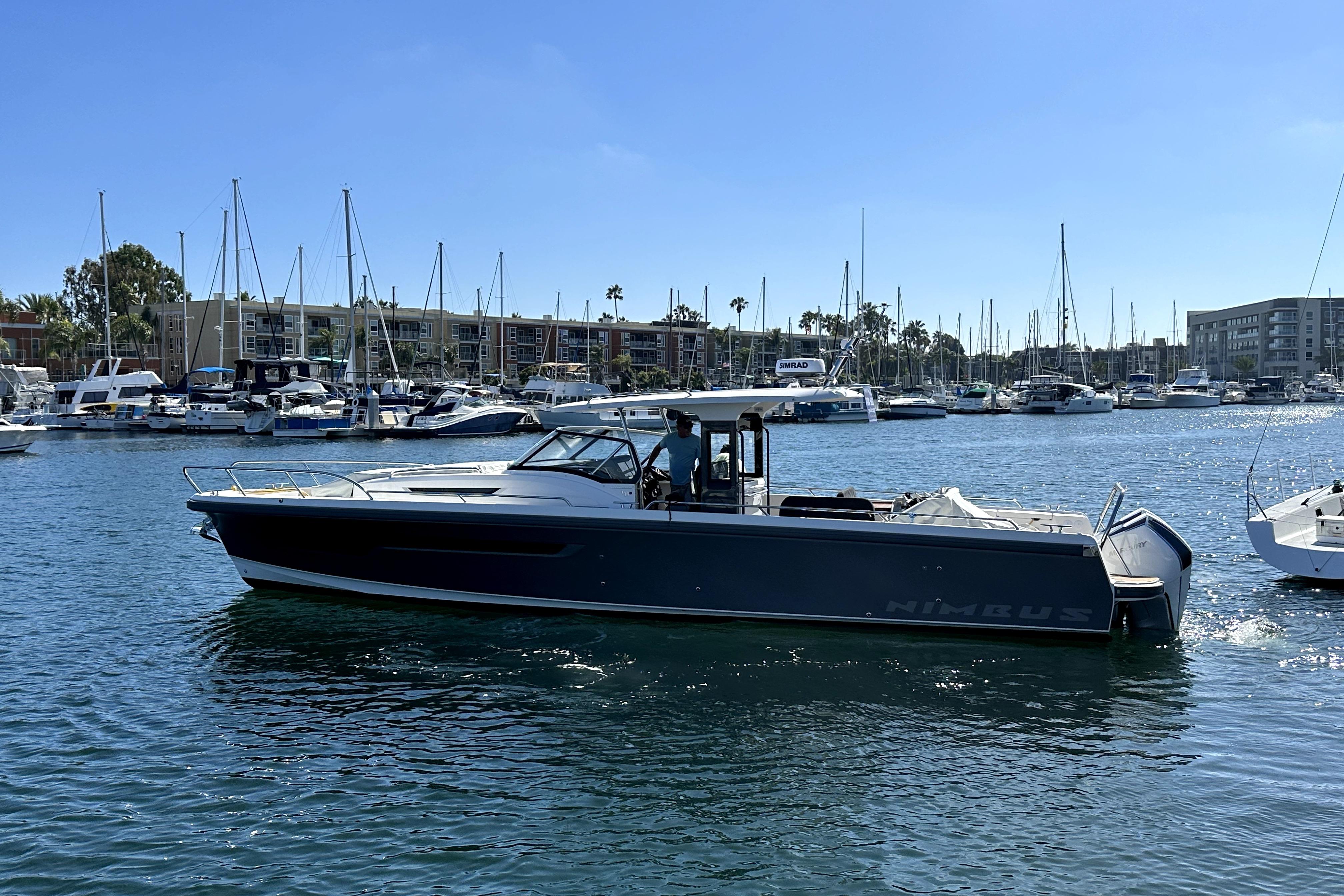 2023 Nimbus T11 boat cruising in a marina with sailboats in the background.