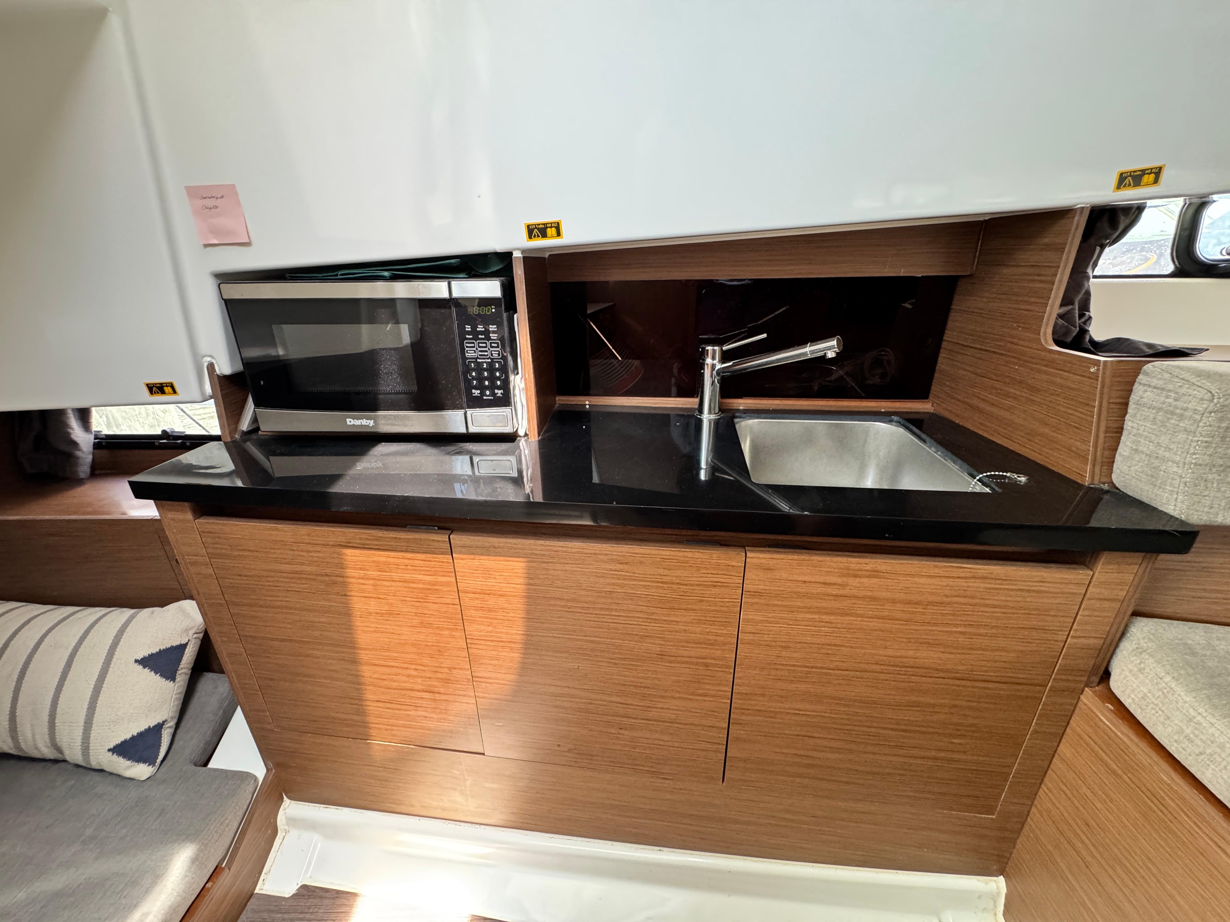 2022 Beneteau Flyer 9 SUNdeck interior kitchen with microwave, sink, and wooden cabinetry.