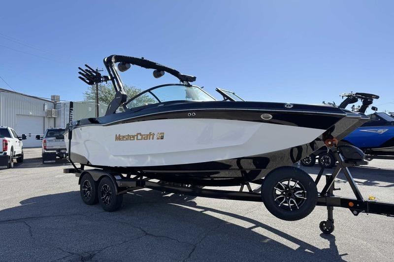 2026 MasterCraft XT22 boat on trailer, parked outdoors under clear blue sky.