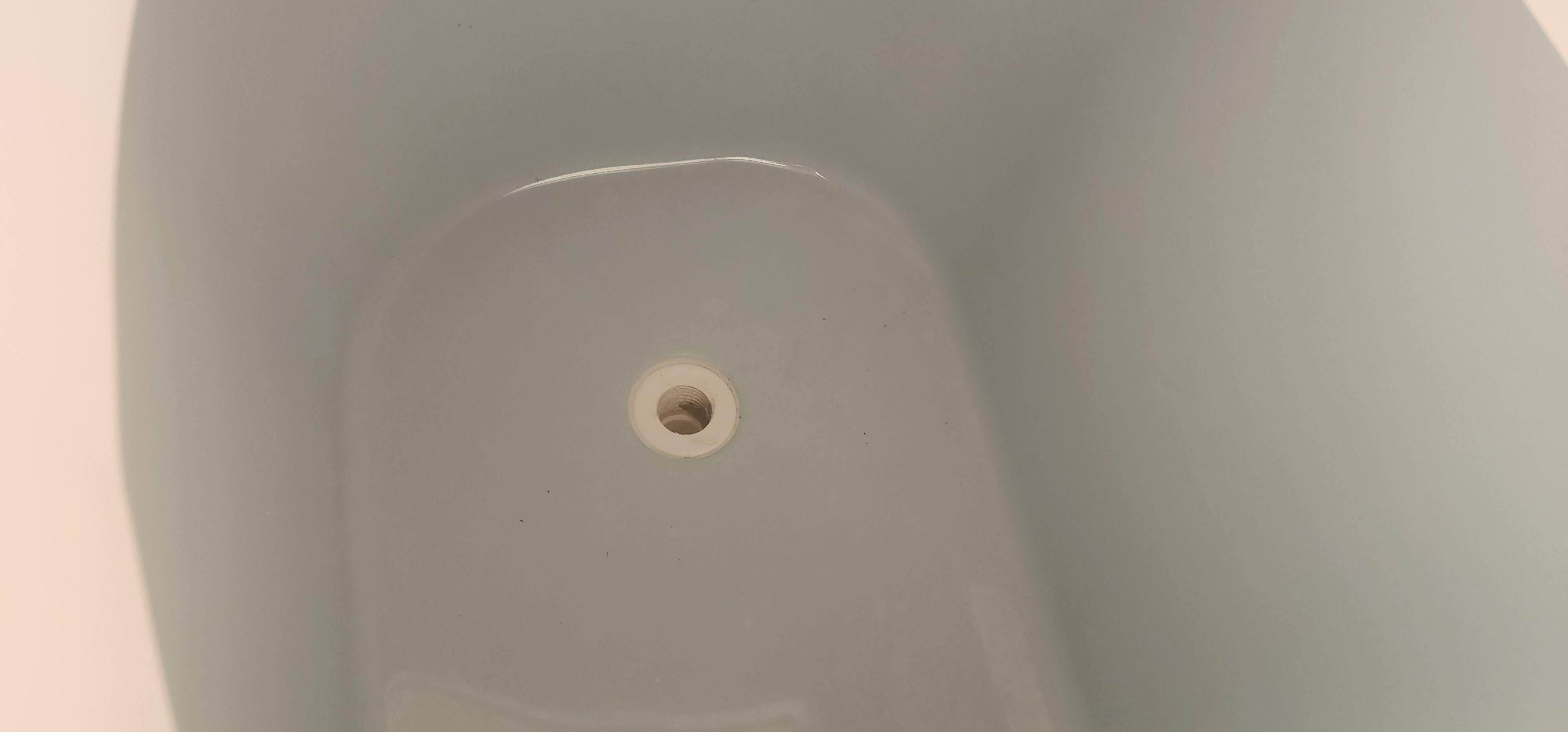Close-up of a boat drain in a white, smooth area.