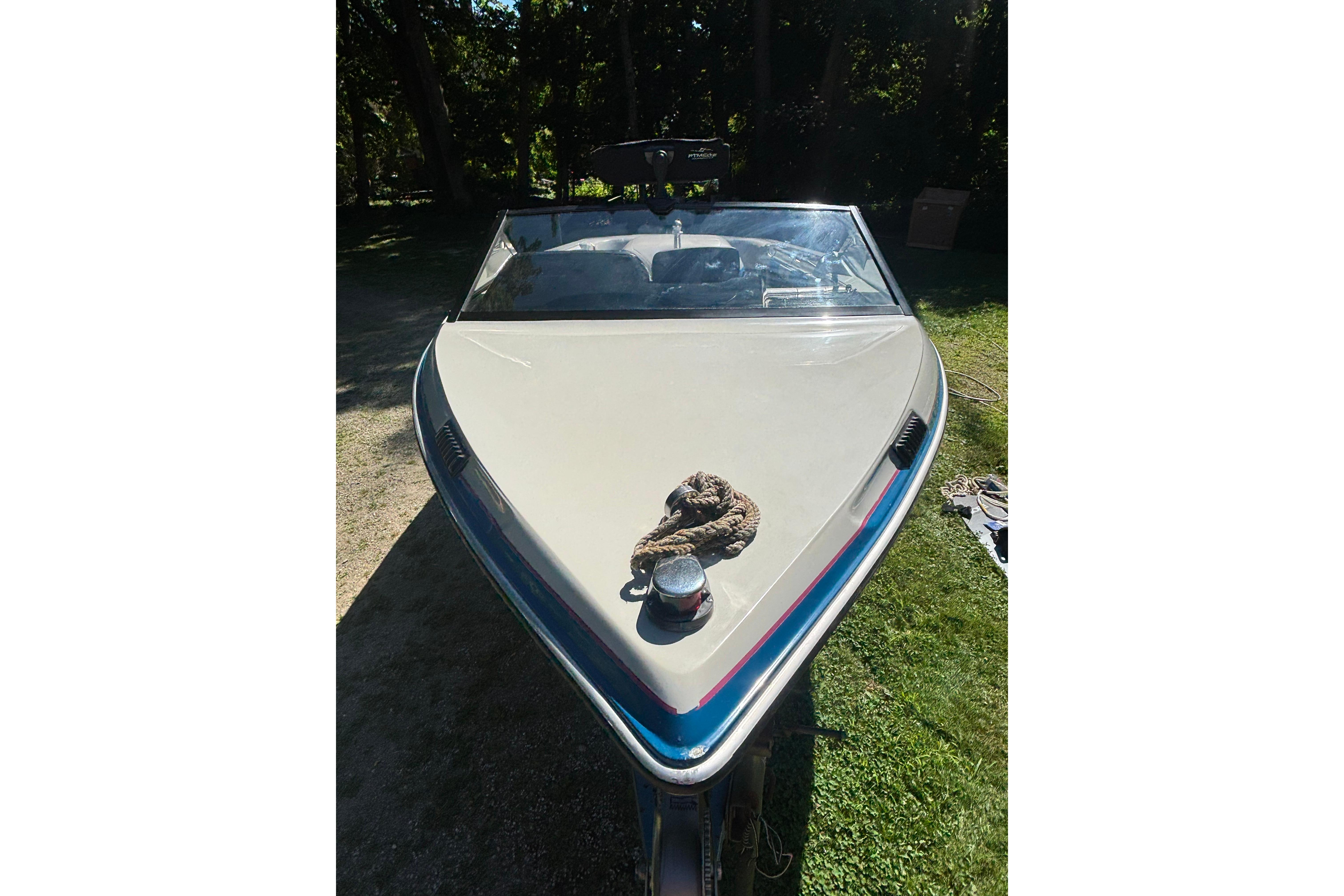 1990 MasterCraft ProStar 190 boat, front view, parked on grass with coiled rope.