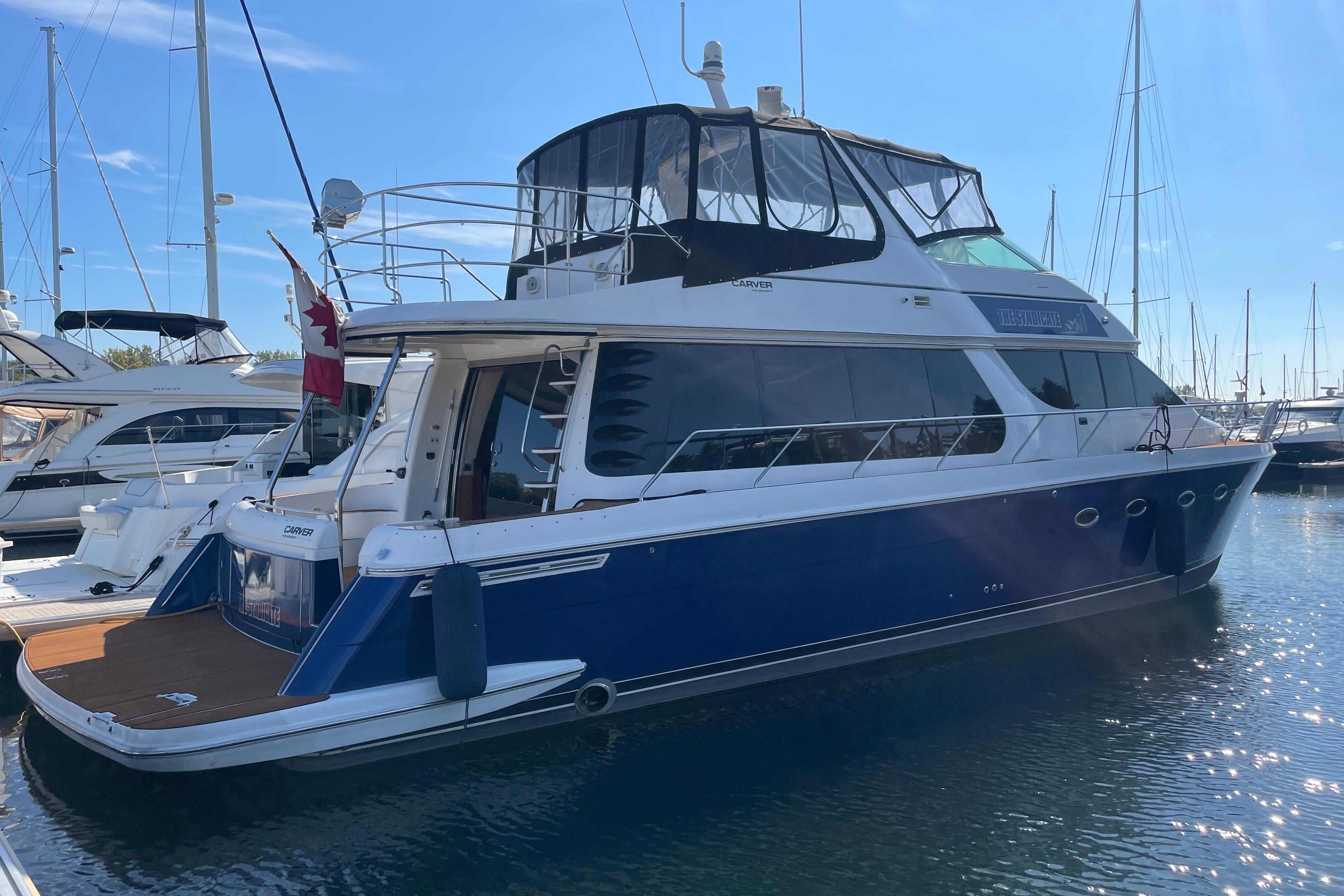 2002 Carver 570 Voyager Pilothouse yacht docked in a marina under clear blue skies.
