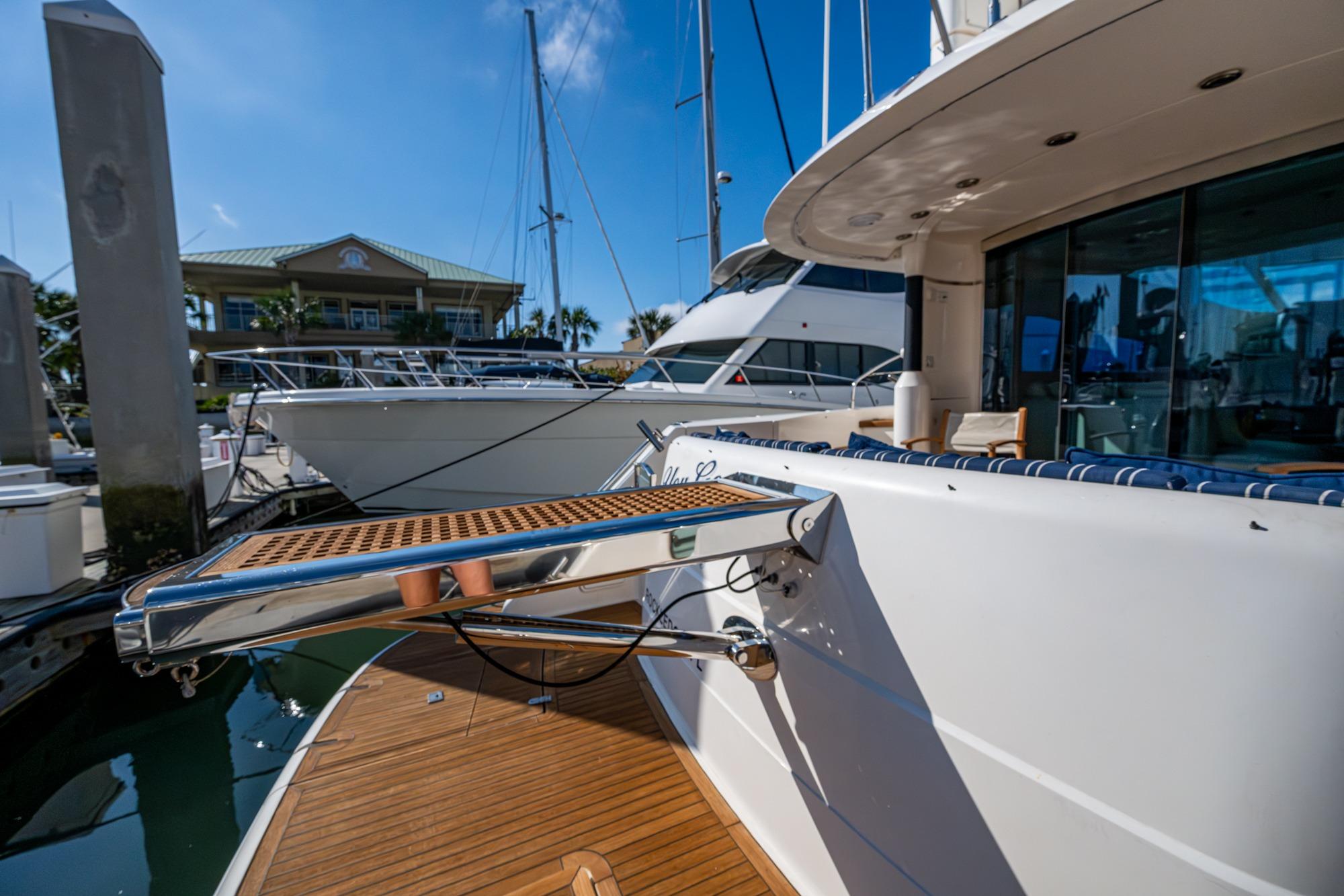 Luxury yacht Fairline Squadron 52, 2000 model, docked at marina under clear blue sky.