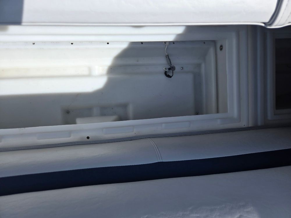 A white storage compartment on a boat with a cushioned seating area.