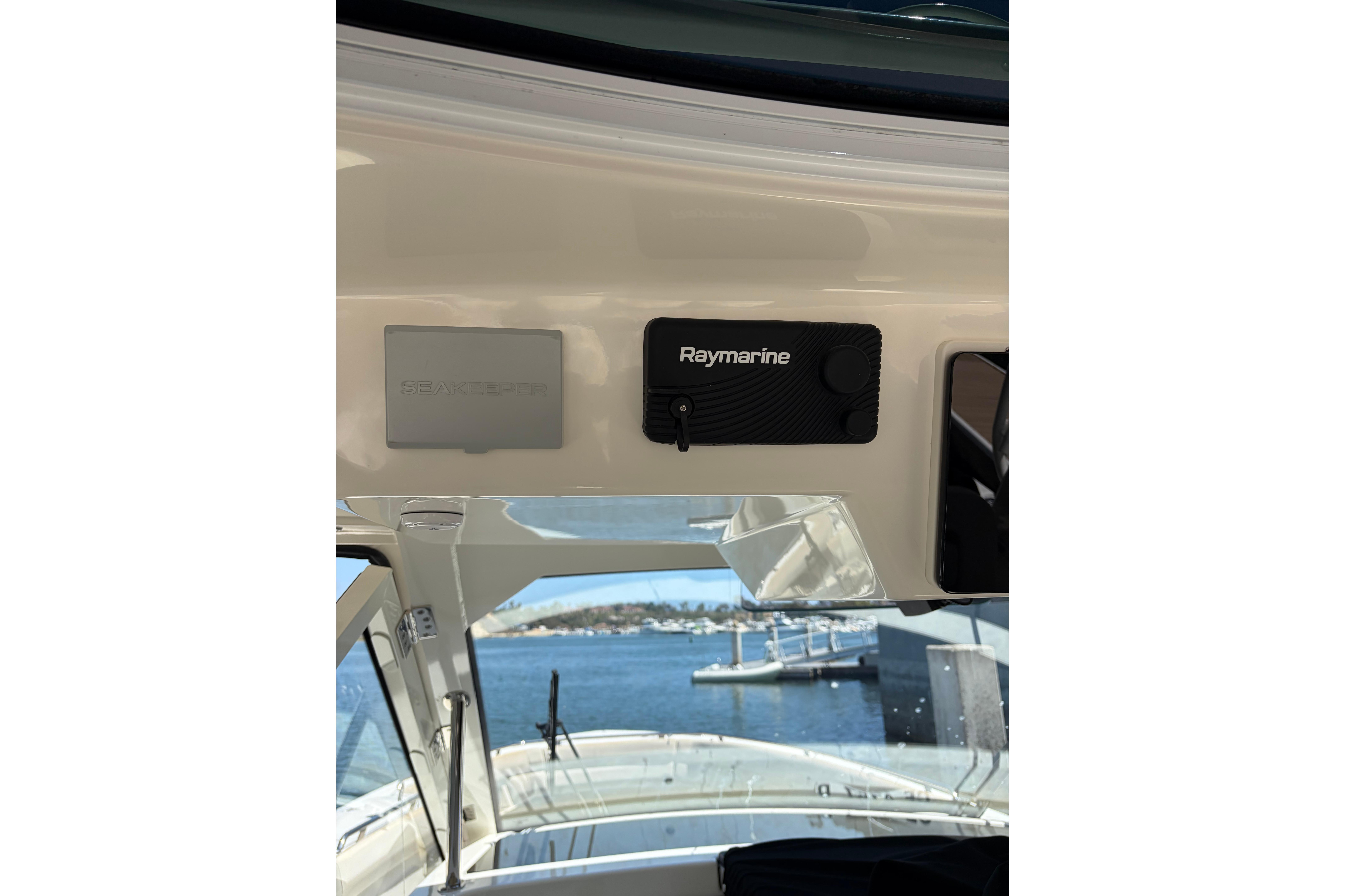 2020 Boston Whaler 380 Realm dashboard with Raymarine and Seakeeper controls, overlooking marina.