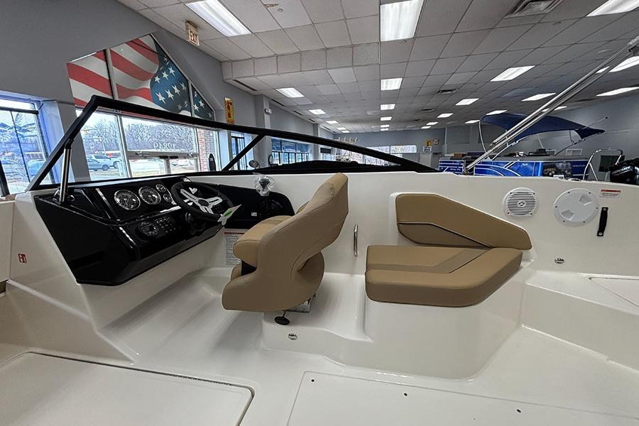 2026 Bayliner V20 boat interior with beige seating and modern dashboard in showroom.