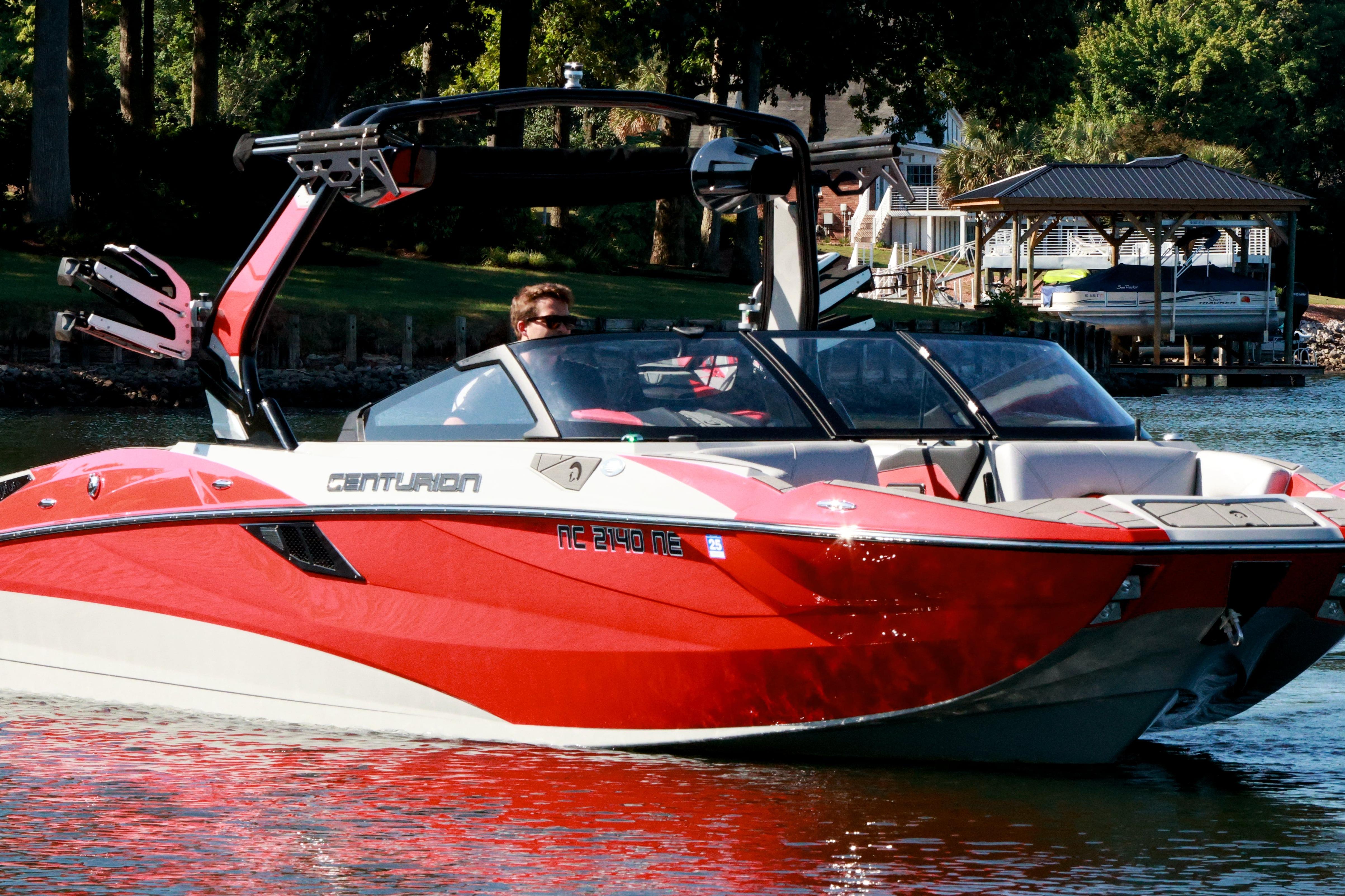 2024 Centurion Fi23 boat in vibrant red on a serene lake.