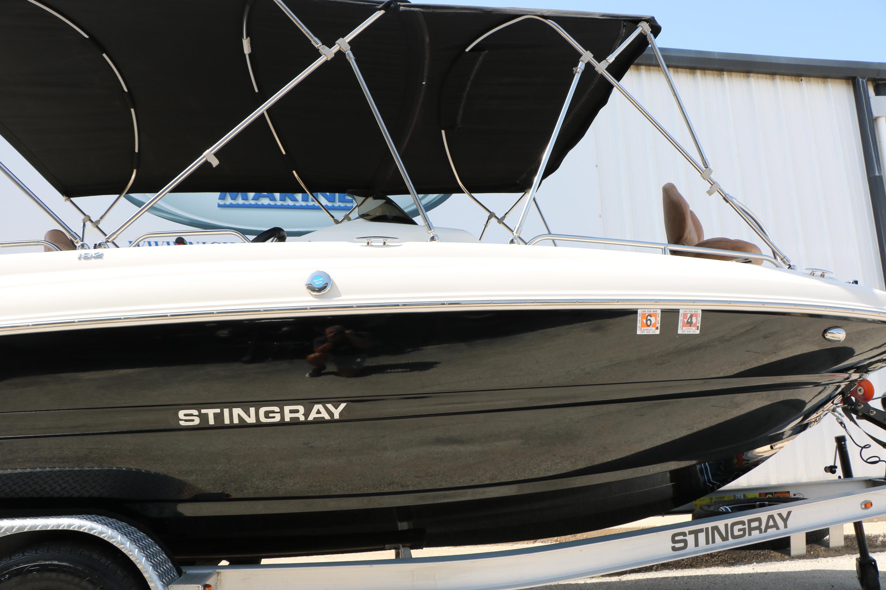 2022 Stingray 192 SC boat with black hull and canopy, displayed on a trailer.