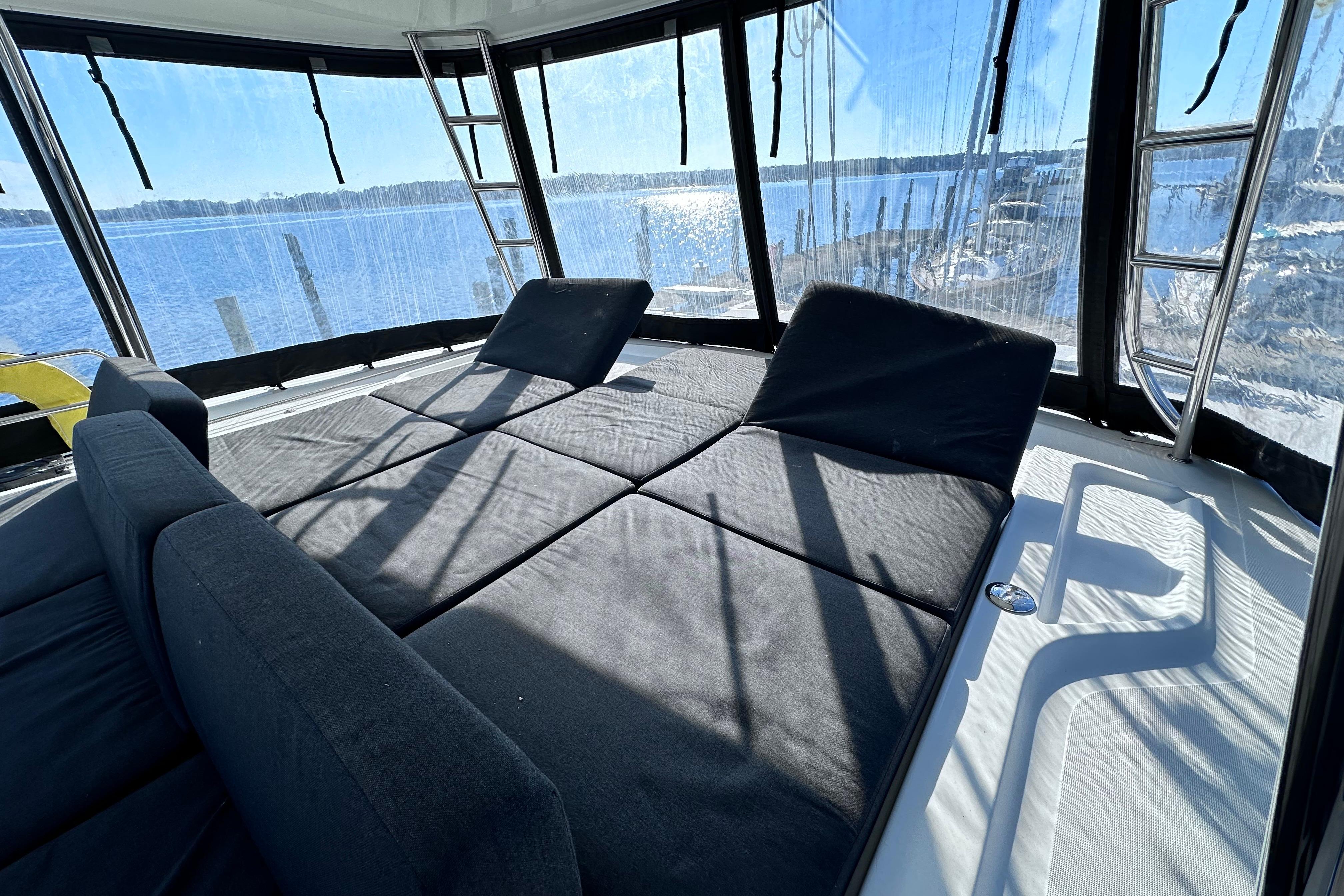 2023 Lagoon 50 yacht interior with sunlit lounge area and panoramic windows.