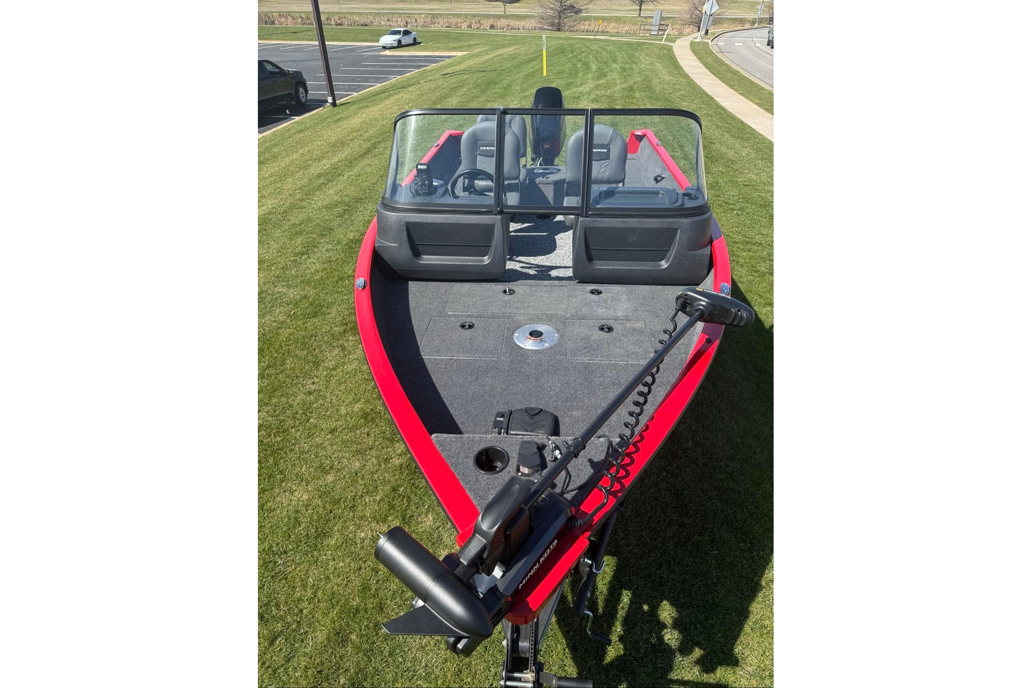 2026 Tracker Pro Guide V-16 WT boat with red trim, parked on grass.